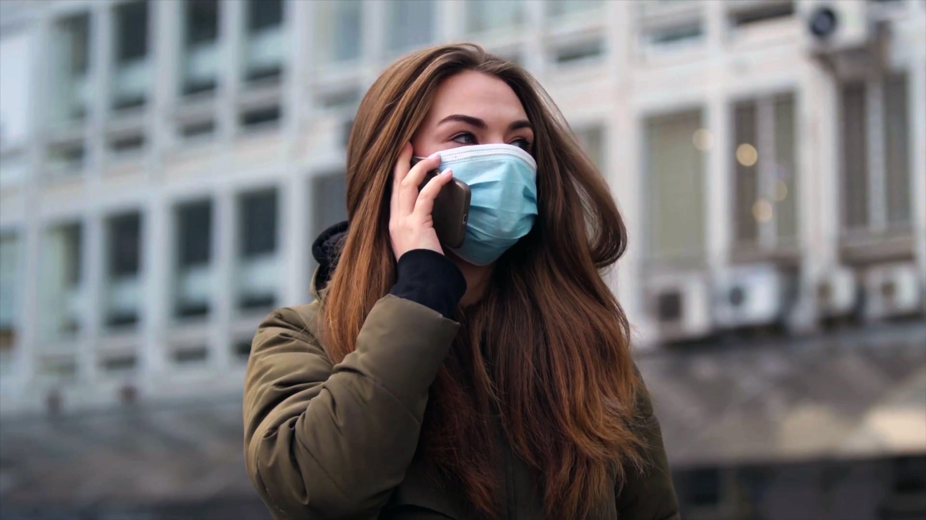 Young woman wearing a face mask as a preventive against an airborne virus, bacteria, coronavirus speaking on her mobile phone in street.