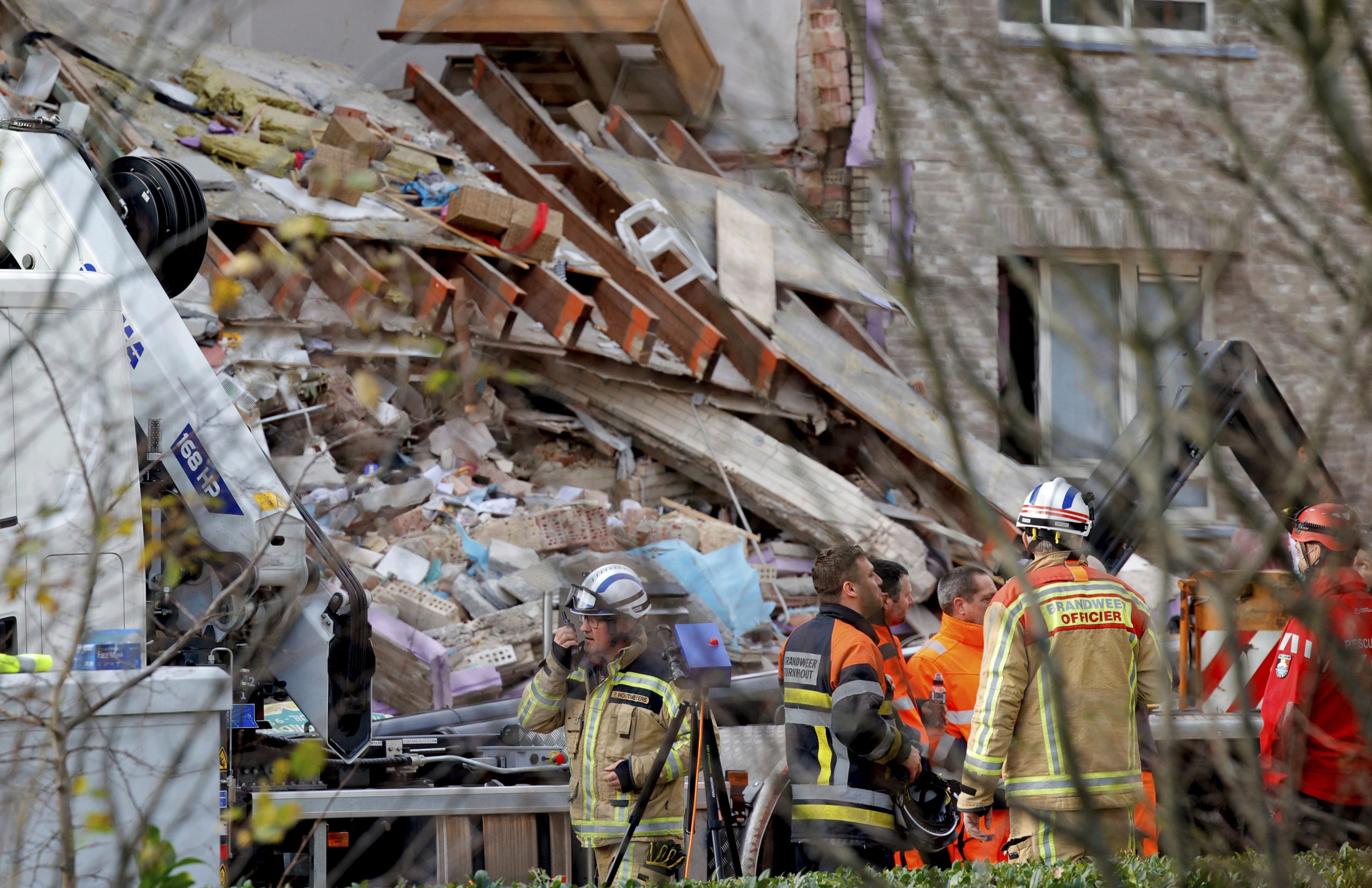 Rescue workers look up at rubble scattered in front of a building after a blast occurred in Turnhout, Belgium, Friday, Dec. 31, 2021. Rescue services said it was still unclear what caused the blast or if there are casualties. (AP Photo/Olivier Matthys)