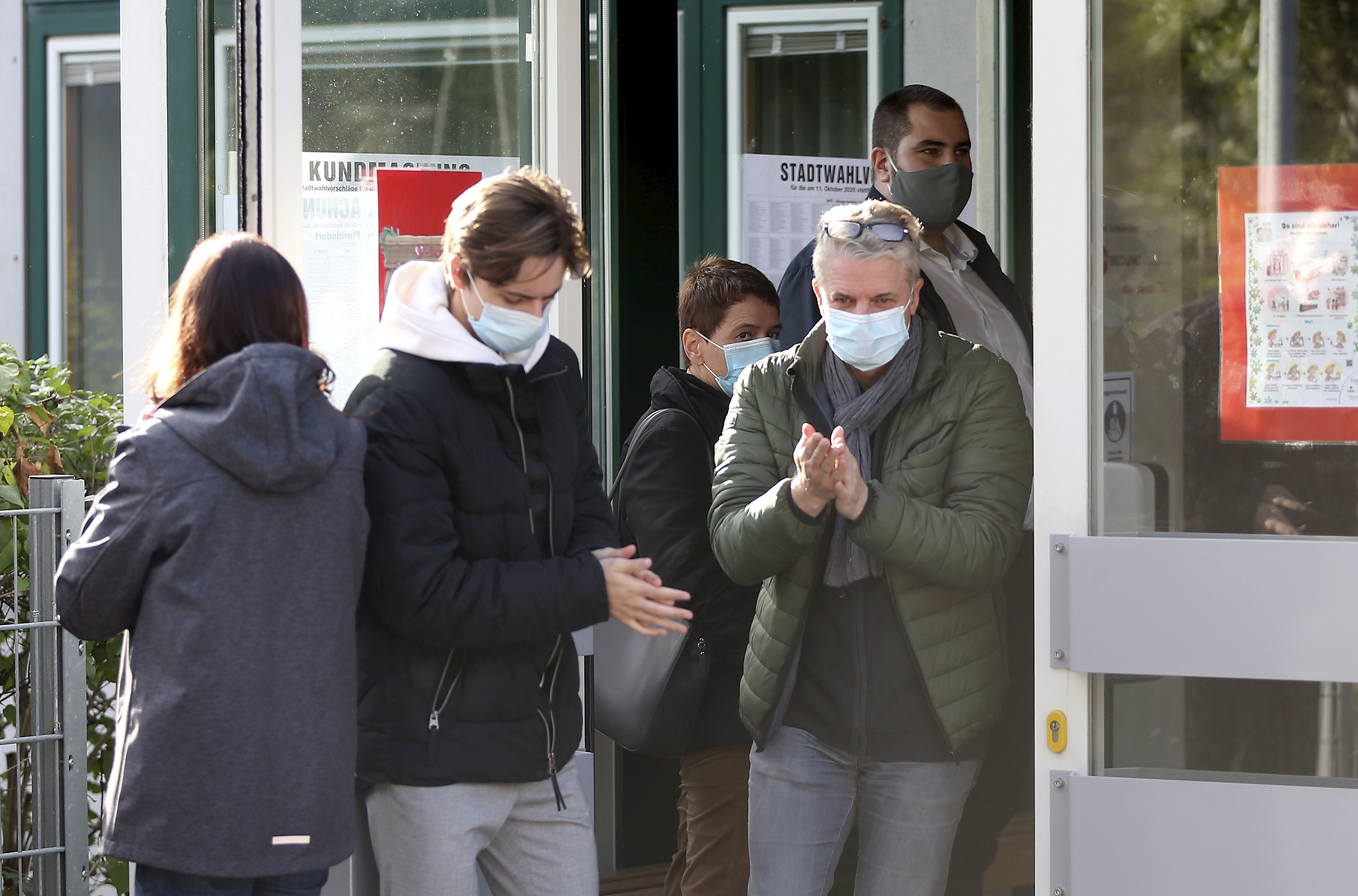 People with face masks leave a polling station to the local elections in Vienna, Austria, Sunday, Oct. 11, 2020. (AP Photo/Ronald Zak)