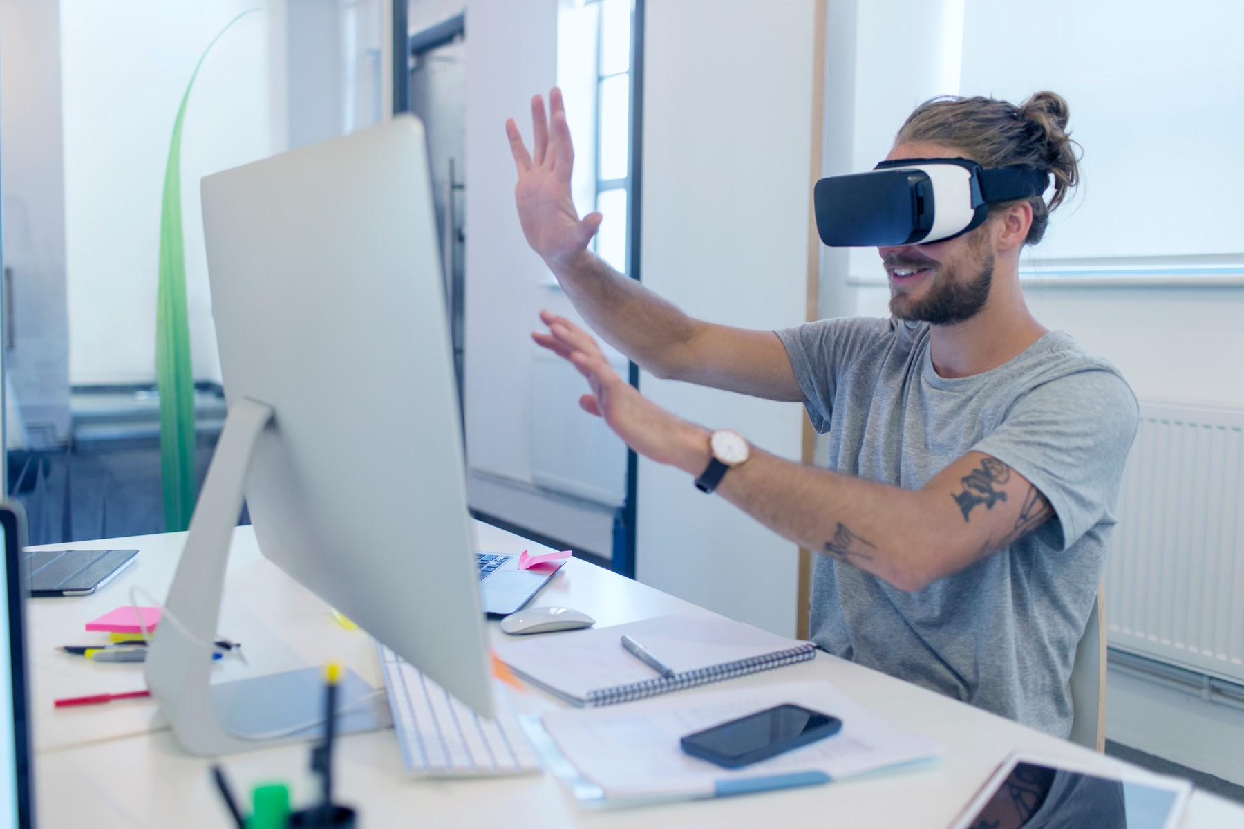 Male computer programmer programming virtual reality simulator glasses at computer in office