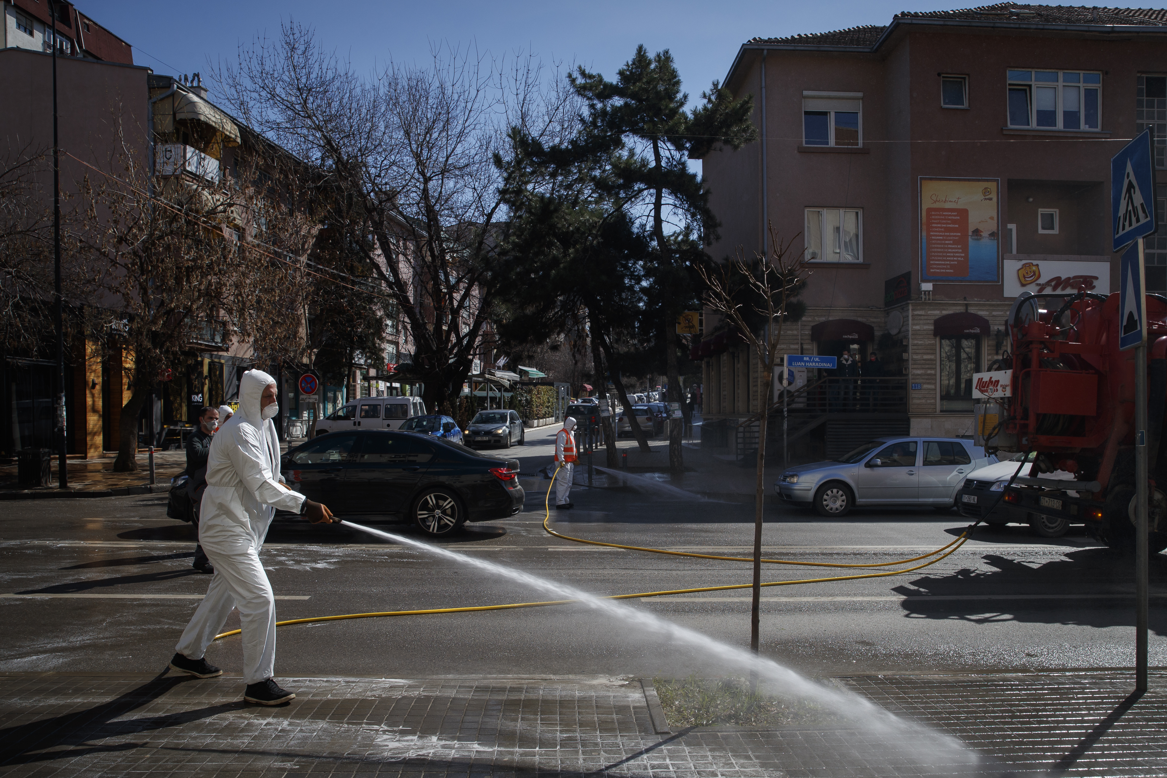 epa08300155 An employee wearing a protective body suit cleans the streets to prevent spread of the coronavirus SARS-CoV-2, which causes the COVID-19 disease, in Pristina, Kosovo, 17 March 2020.  EPA-EFE/VALDRIN XHEMAJ