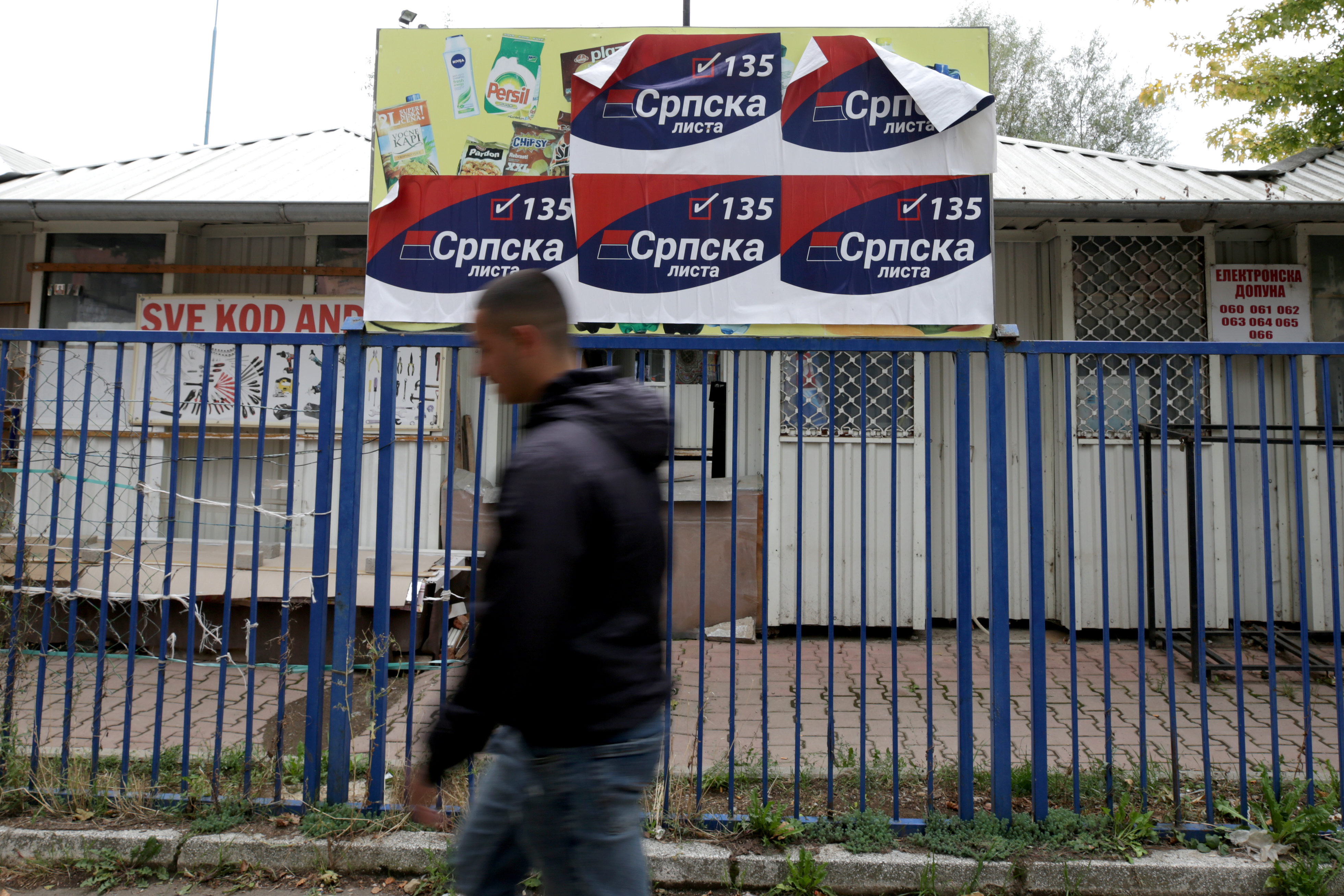 A person walks past campaign posters of 'Serb List' political party in Mitrovica, Kosovo, October 5, 2019. REUTERS/Florion Goga - RC128489A210