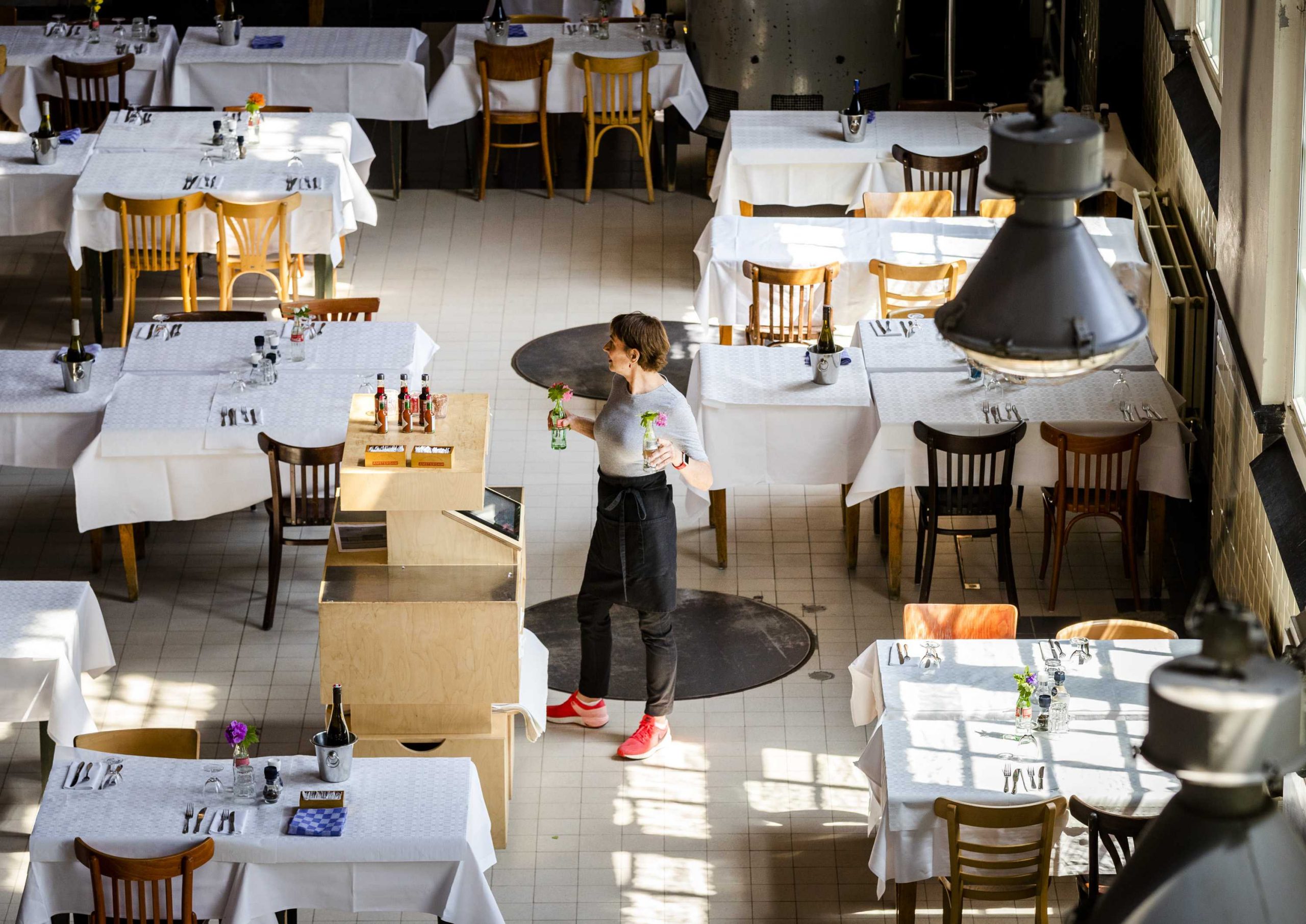 epa08444870 An employee prepares for the reopening of the catering industry in a cafe-restaurant in Amsterdam, The Netherlands, 26 May 2020. The cafe-restaurant wants to let guests dine coronaproof with social distance of 1.5 meter.  EPA-EFE/REMKO DE WAAL