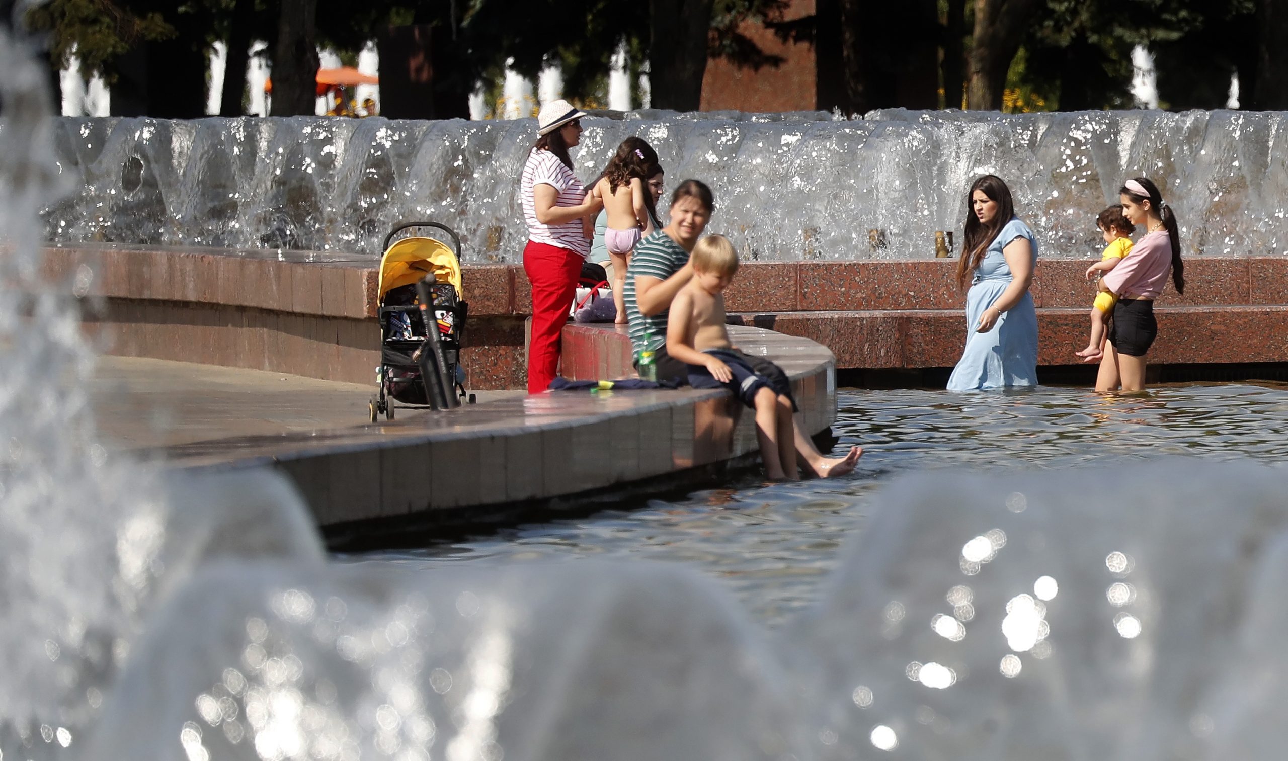 epa09371459 People sit by a water fountain at the Poklonnaya hill in Moscow, Russia, 27 July 2021. The temperature exceeded 29 degrees Celsius in Russian capital.  EPA-EFE/MAXIM SHIPENKOV