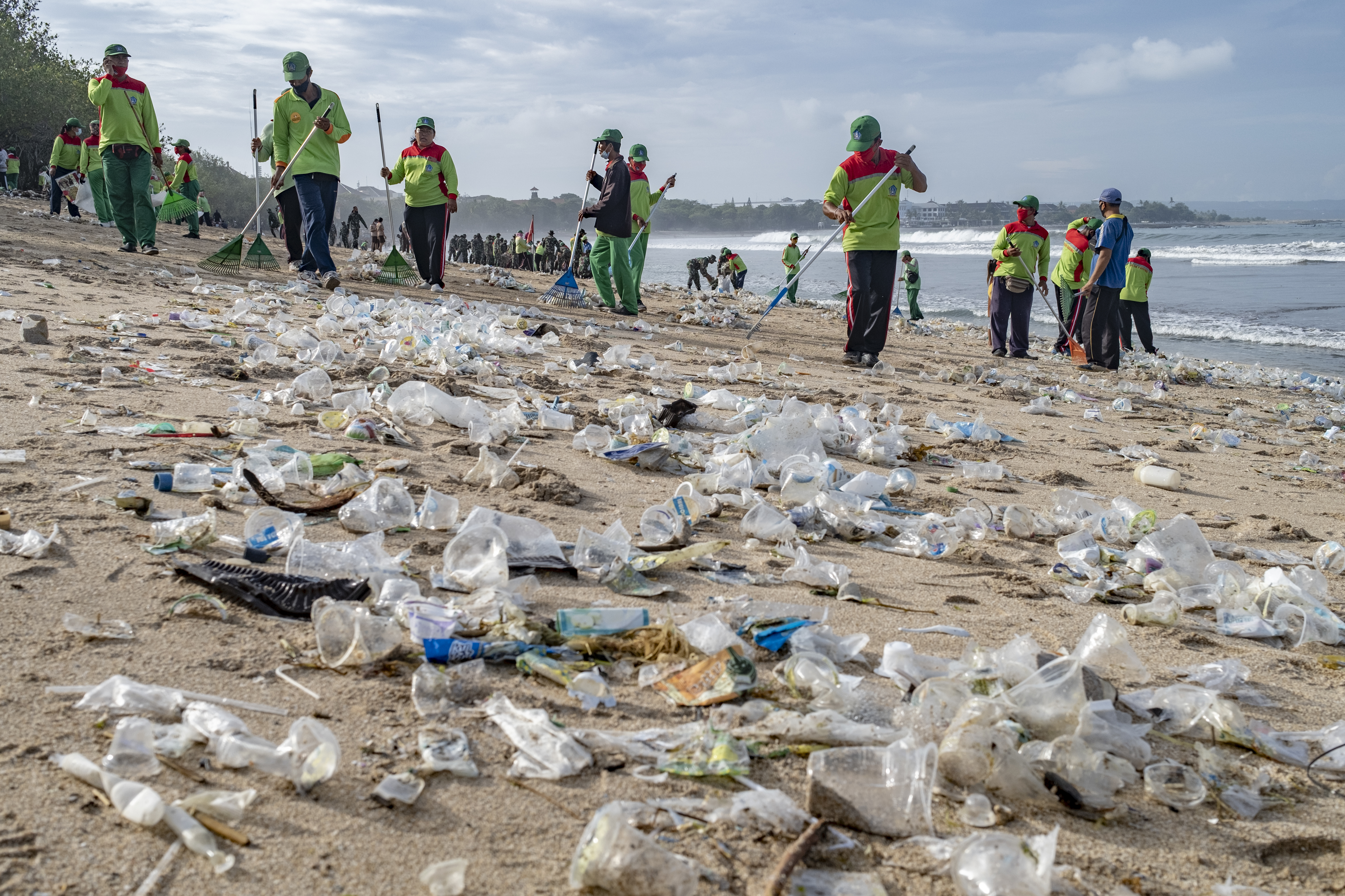 epaselect epa08913584 Workers clean up piles of debris and plastic waste brought in by strong waves at Kuta Beach in Bali, Indonesia, 01 January 2021.  EPA-EFE/MADE NAGI