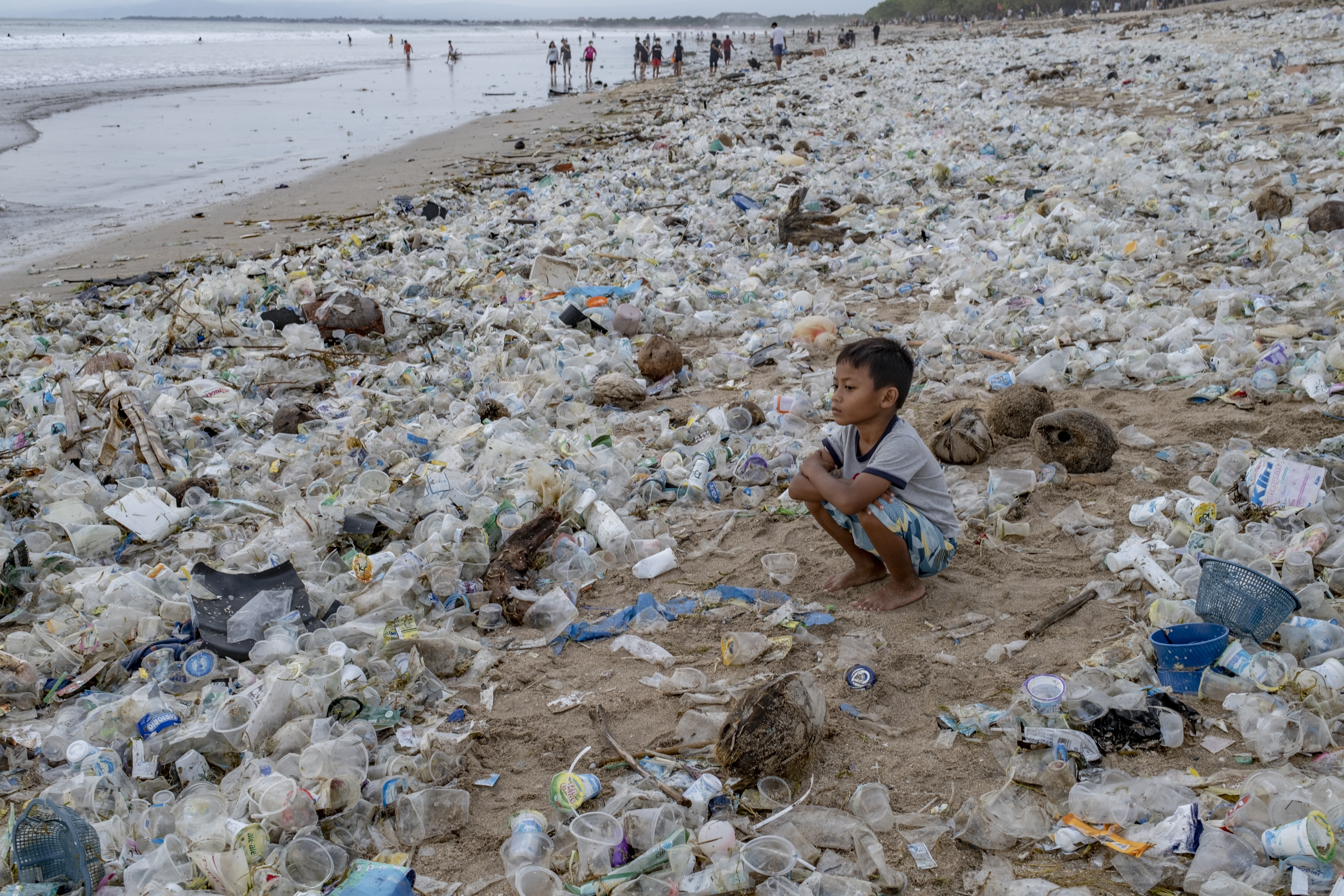 epaselect epa08912370 A boy sits on beach covered in plastic wastes at Kuta Beach in Bali, Indonesia, 31 December 2020.  EPA-EFE/MADE NAGI