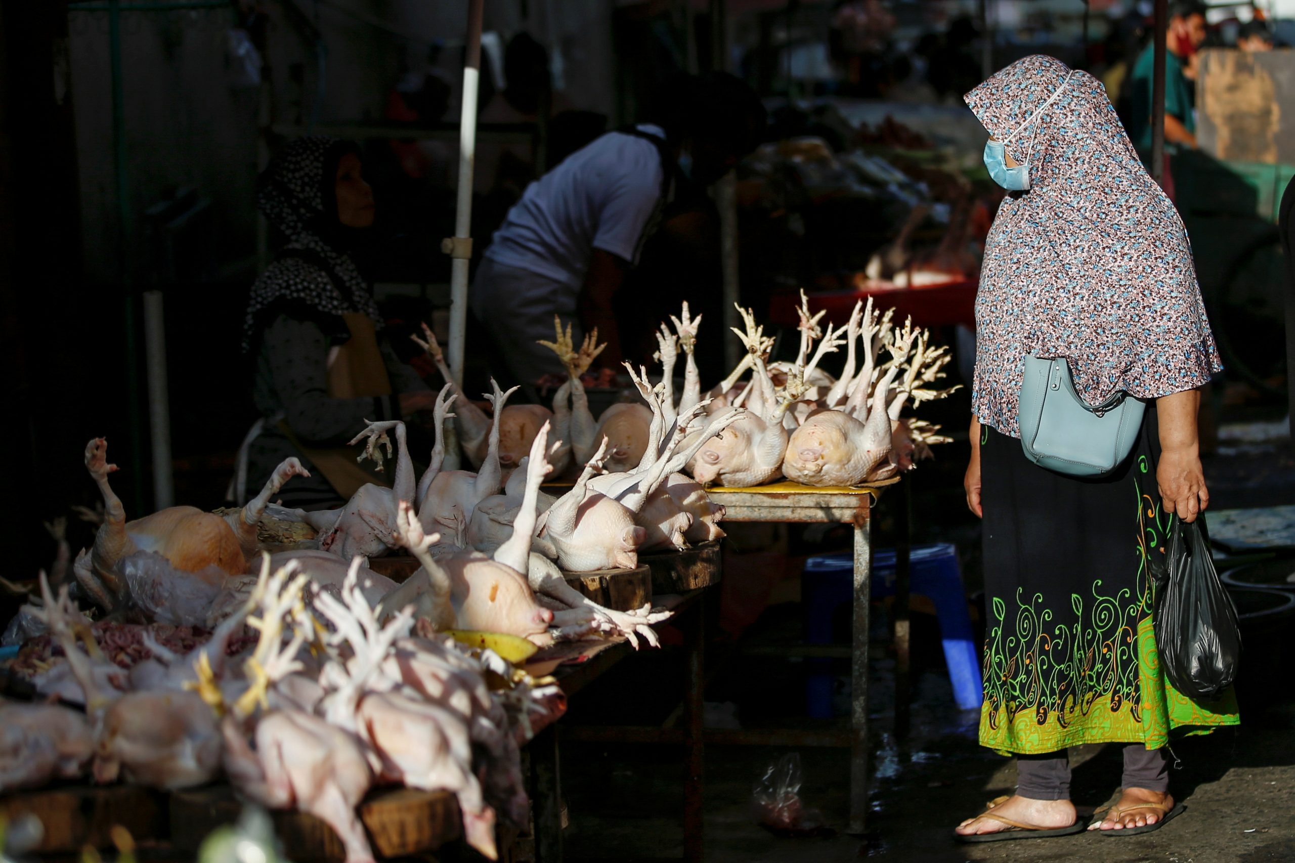 01032021 A woman wearing a protective mask to prevent the spread of coronavirus disease (COVID-19) shops for chickens at a traditional market in Jakarta, Indonesia, March 1, 2021. REUTERS/Willy Kurniawan
