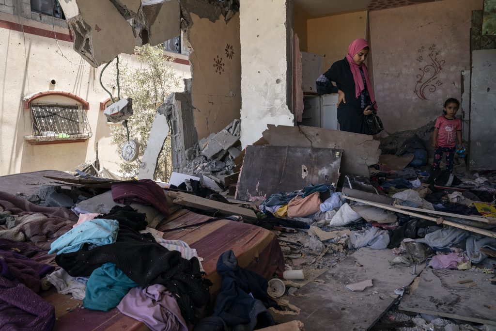 Members of the el-Masri family stand in their front bedroom that was destroyed by Israeli shelling during an 11-day war between Gaza's Hamas rulers and Israel, Wednesday, May 26, 2021, in Beit Hanoun, Gaza Strip. (AP Photo/John Minchillo)
