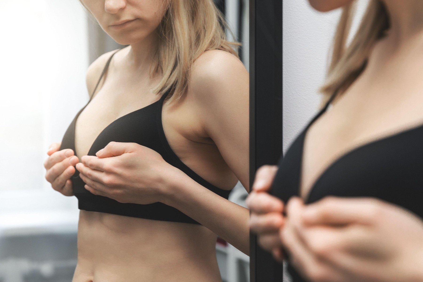 breast health - woman checking her breasts shape in front of the mirror at home