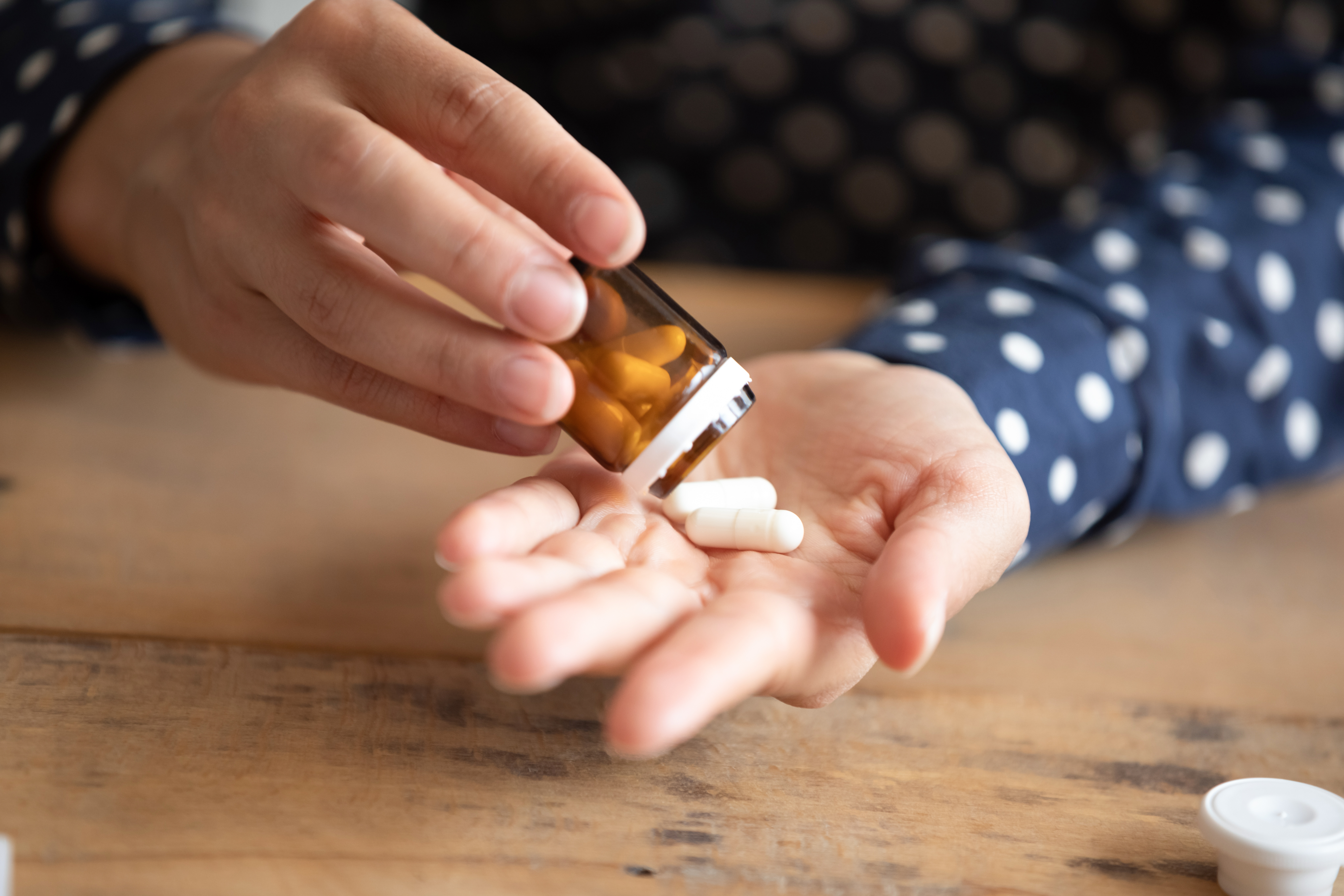 Female,Sit,At,Table,Holding,Bottle,Pour,Into,Palm,Drugs