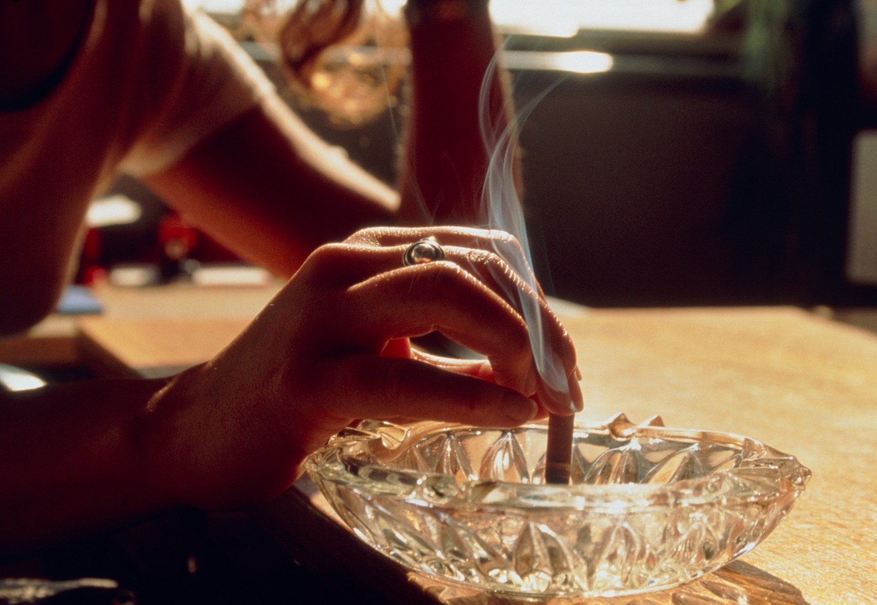 Woman's hand extinguishes cigarette in ashtray