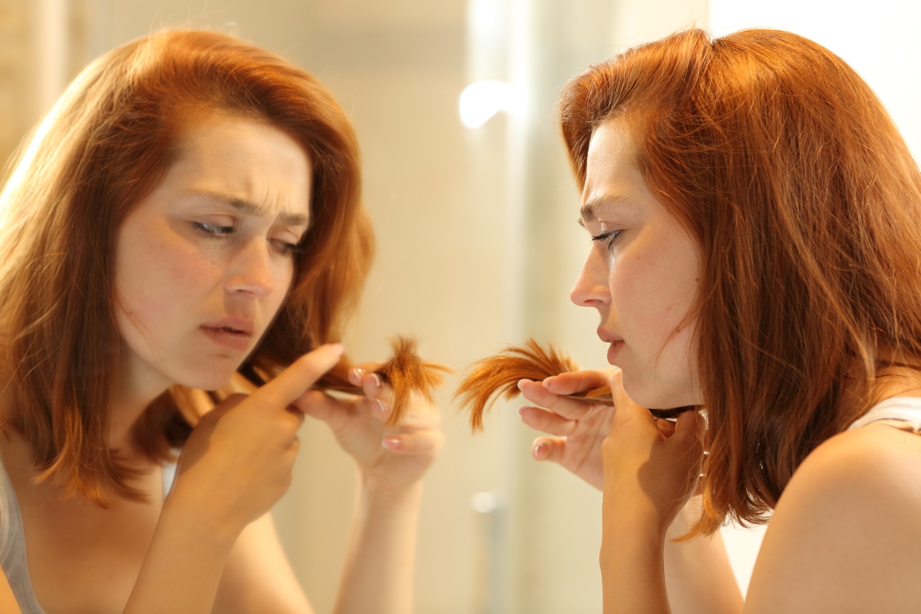 Stressed woman looking at her split hair ends