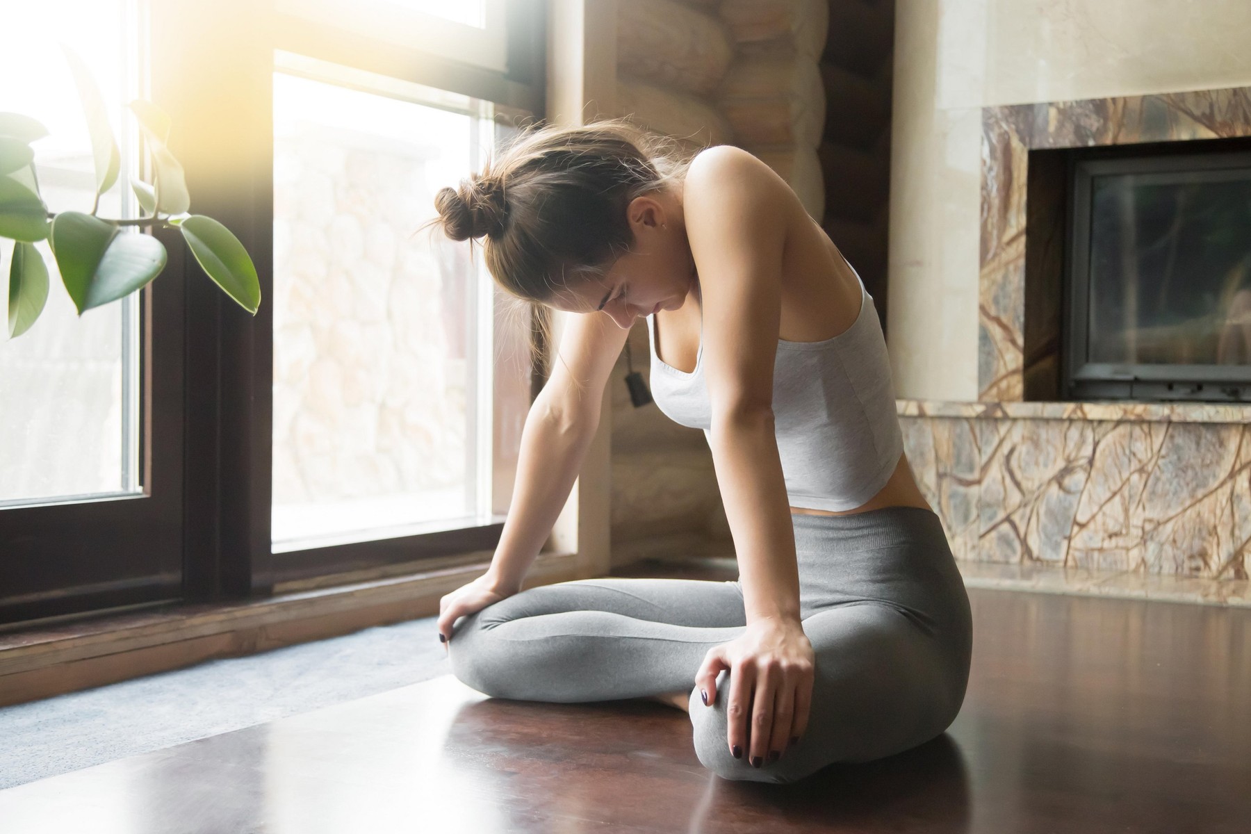 Young attractive woman in Upward Abdominal Lock pose, home inter