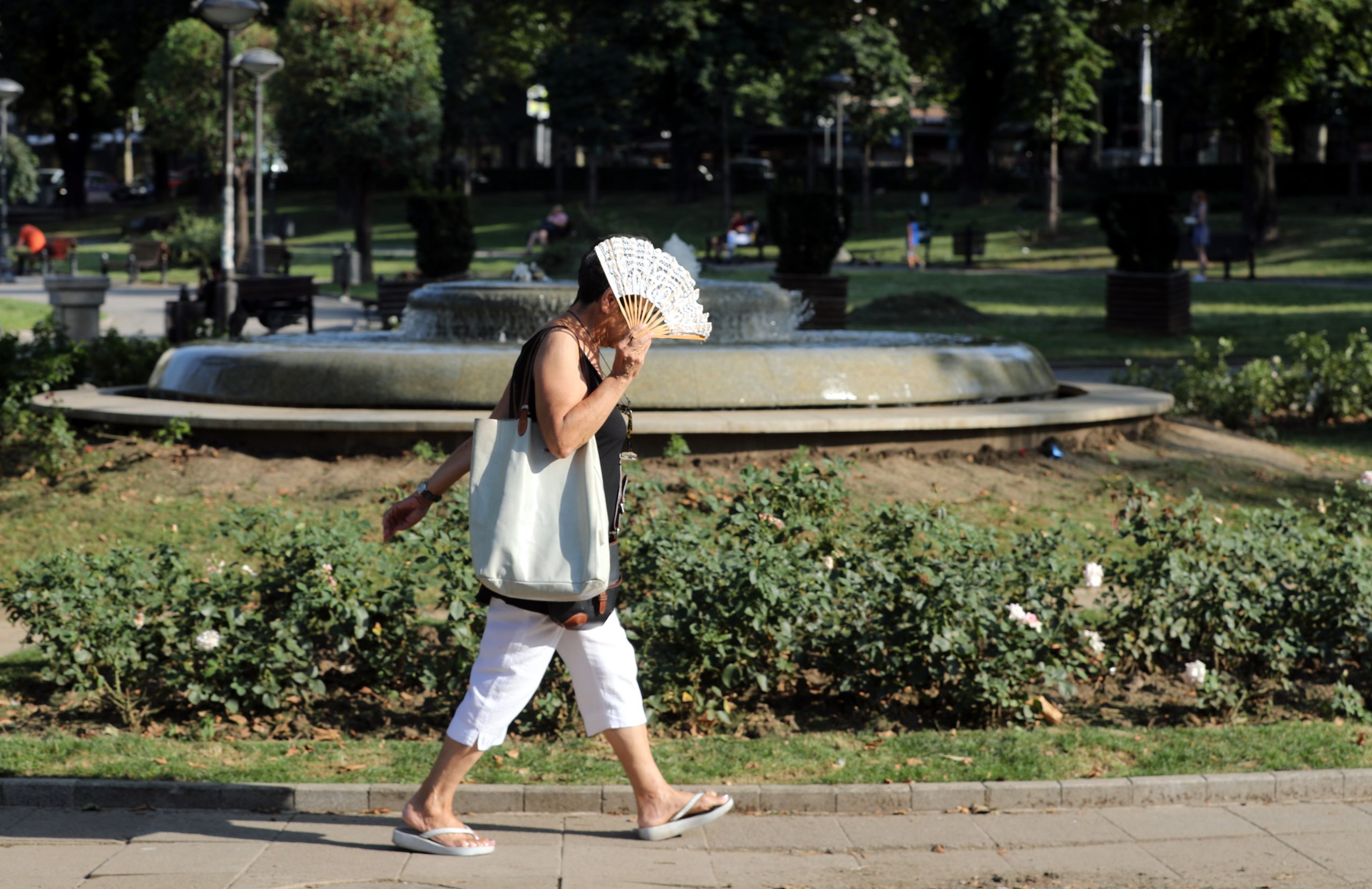 epa07770290 A woman fans herself while walking in the park on a hot day in Belgrade, Serbia, 12 August 2019. Serbia was hit by a heat wave with temperatures reaching 37 degrees Celsius.  EPA-EFE/KOCA SULEJMANOVIC