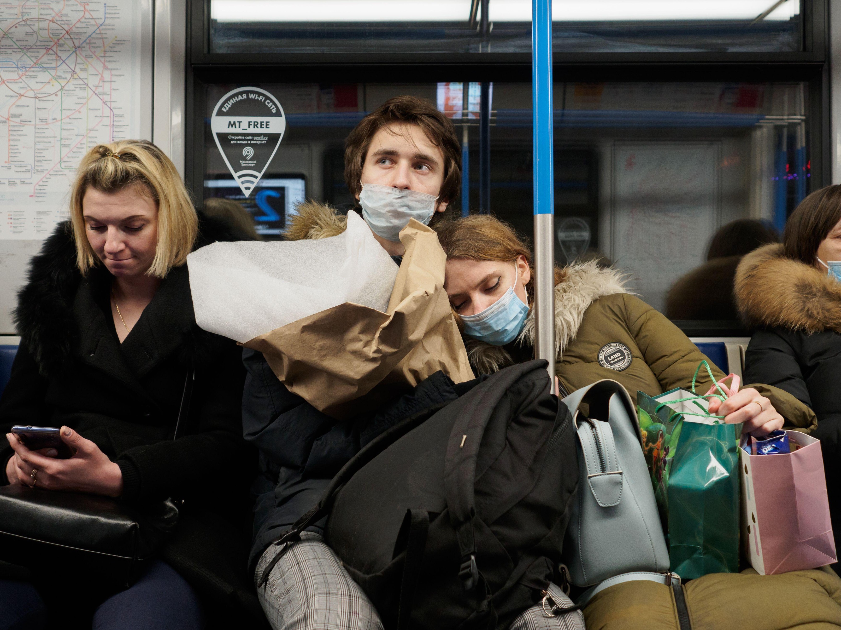 Moscow. Russia. February 25, 2021. Loving young man and woman in medical masks in a subway car. The man gently hugs the woman who has fallen asleep
