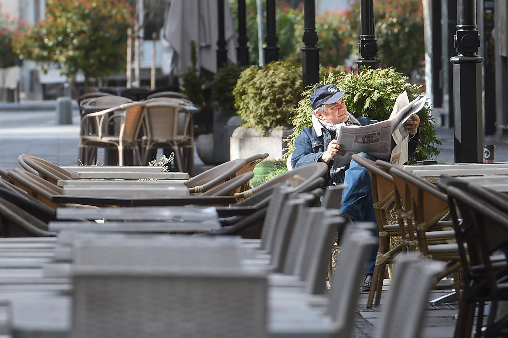 COVEK CITA NOVINE U PRAZNOJ BASTI KAFICA