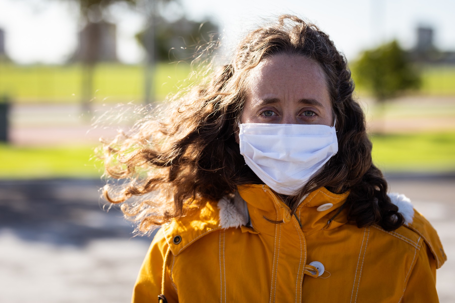 Portrait of Caucasian woman out and about in the city streets during the day, wearing a face mask against covid19 coronavirus standing and looking straight to camera