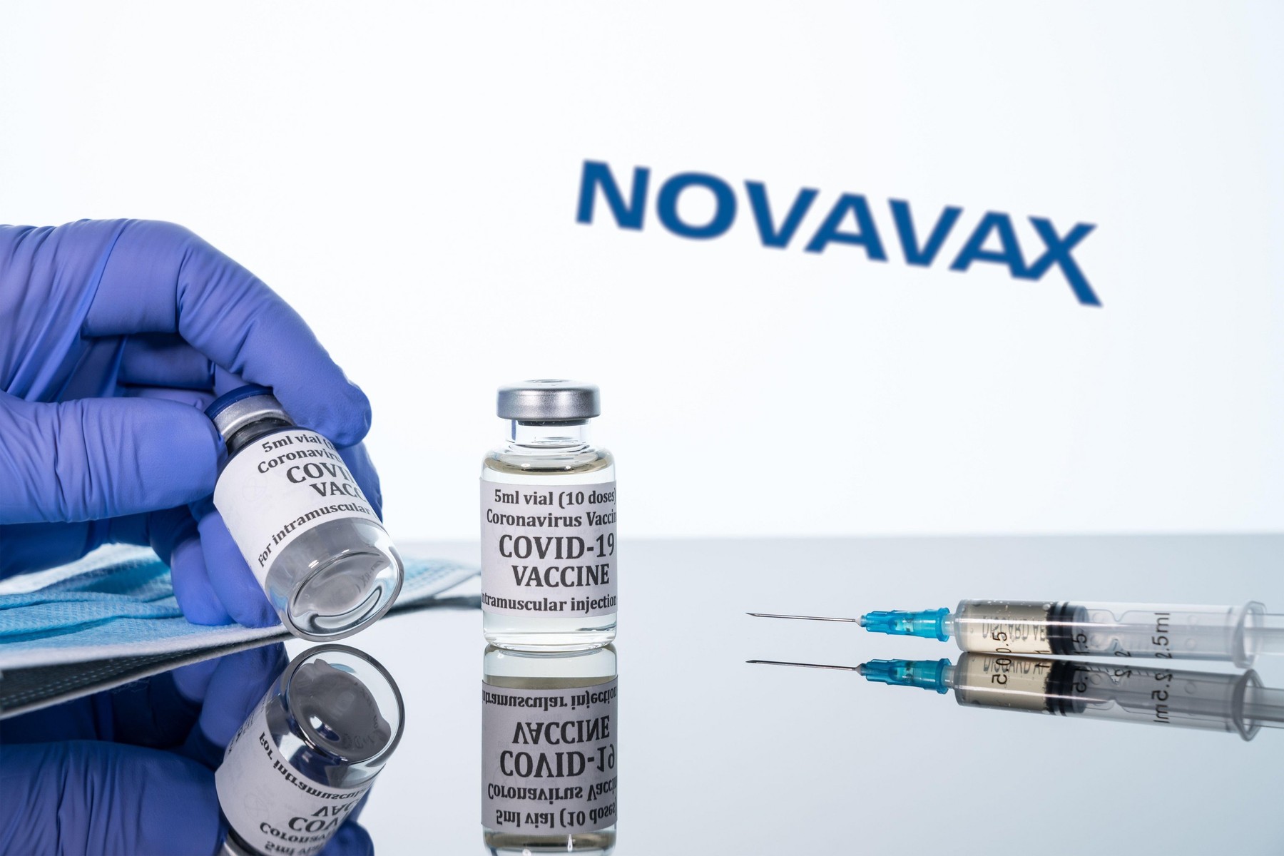 Morgantown, WV - 16 December 2020: Small bottle of coronavirus vaccine with syringe with background of Novavax logo