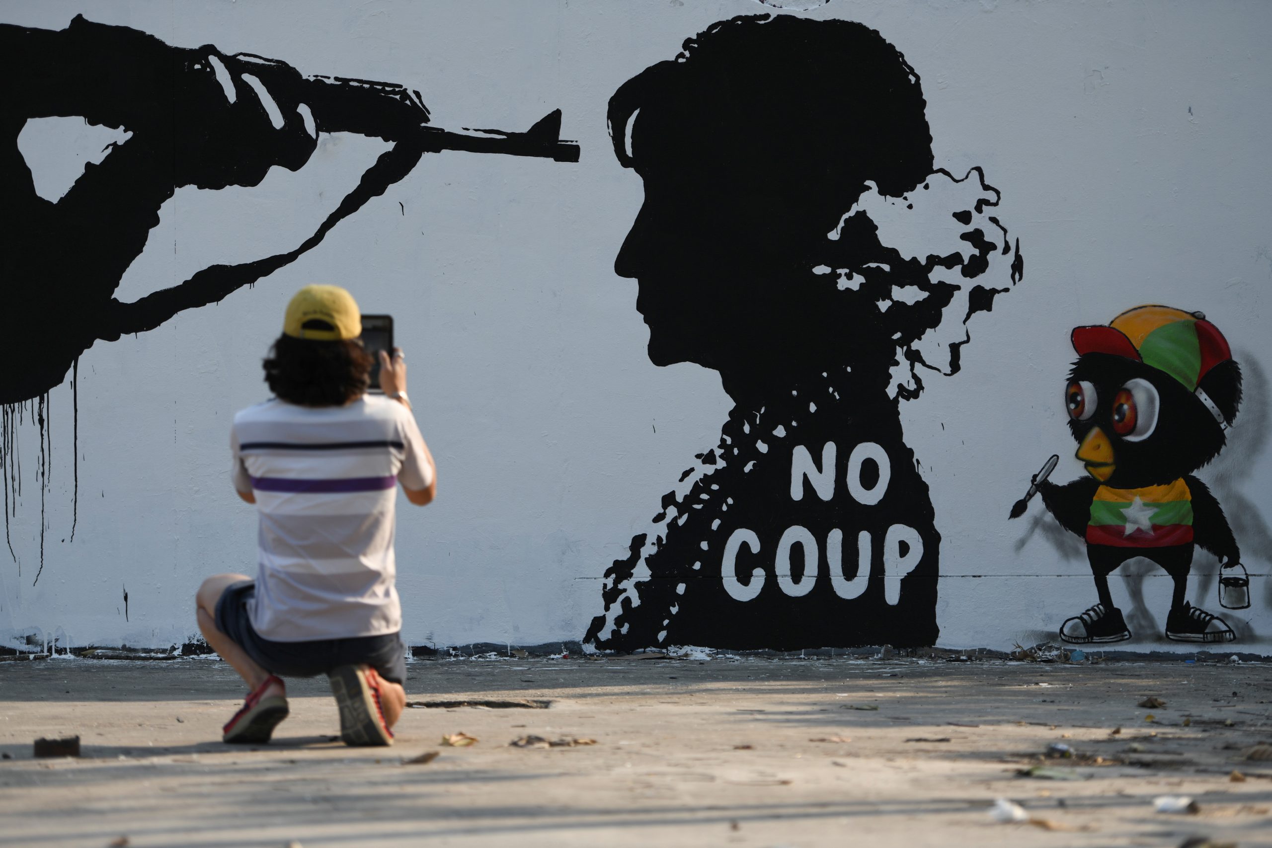 06022021 A man takes a picture of a graffiti by Thai artist Mue Bon against the military coup in Myamar in a street in Bangkok, Thailand, February 6, 2021. REUTERS/Chalinee Thirasupa