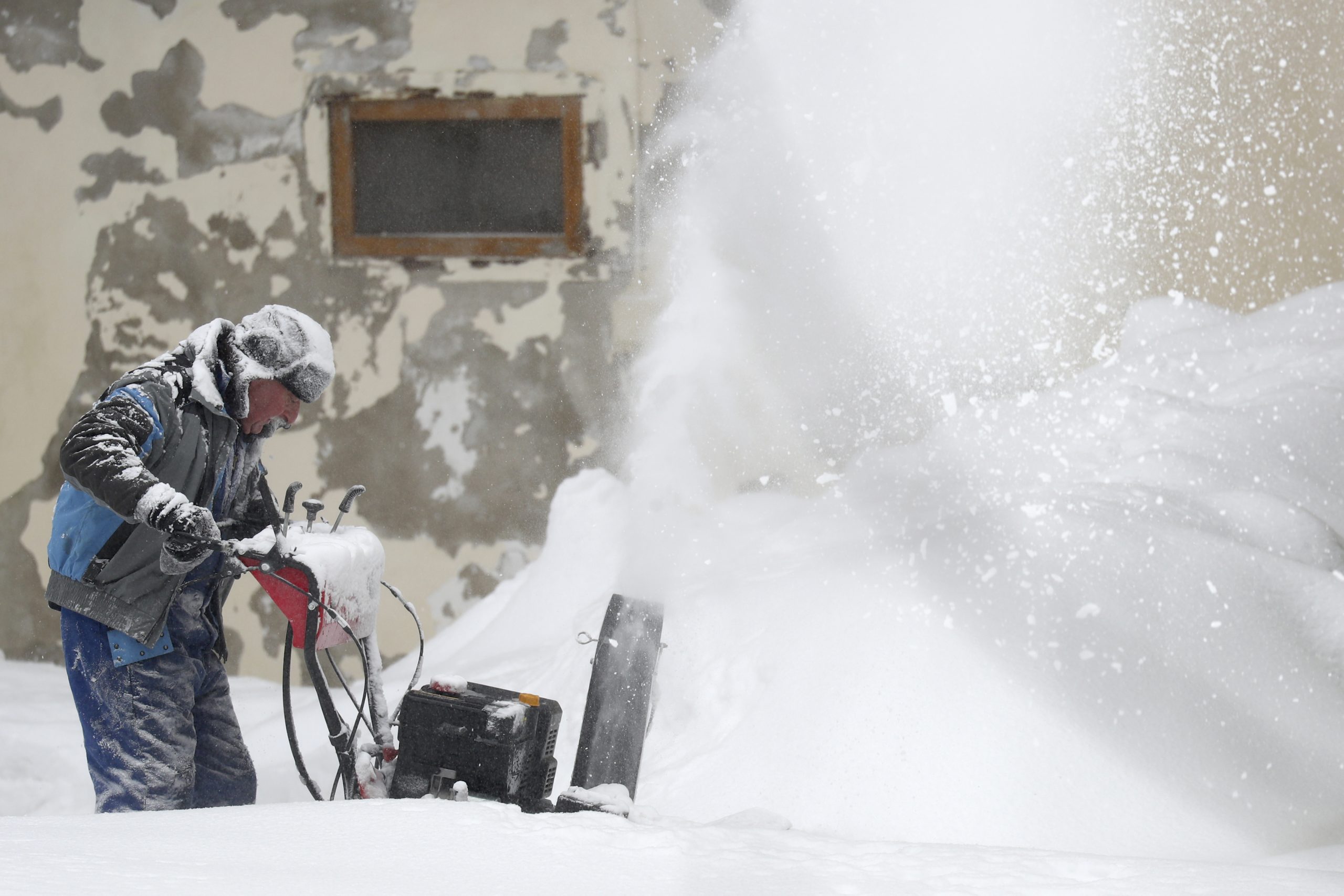 A man blows snow from his driveway at his house near Altenberg, Germany, Monday, Feb. 8, 2021. (AP Photo/Matthias Schrader)
