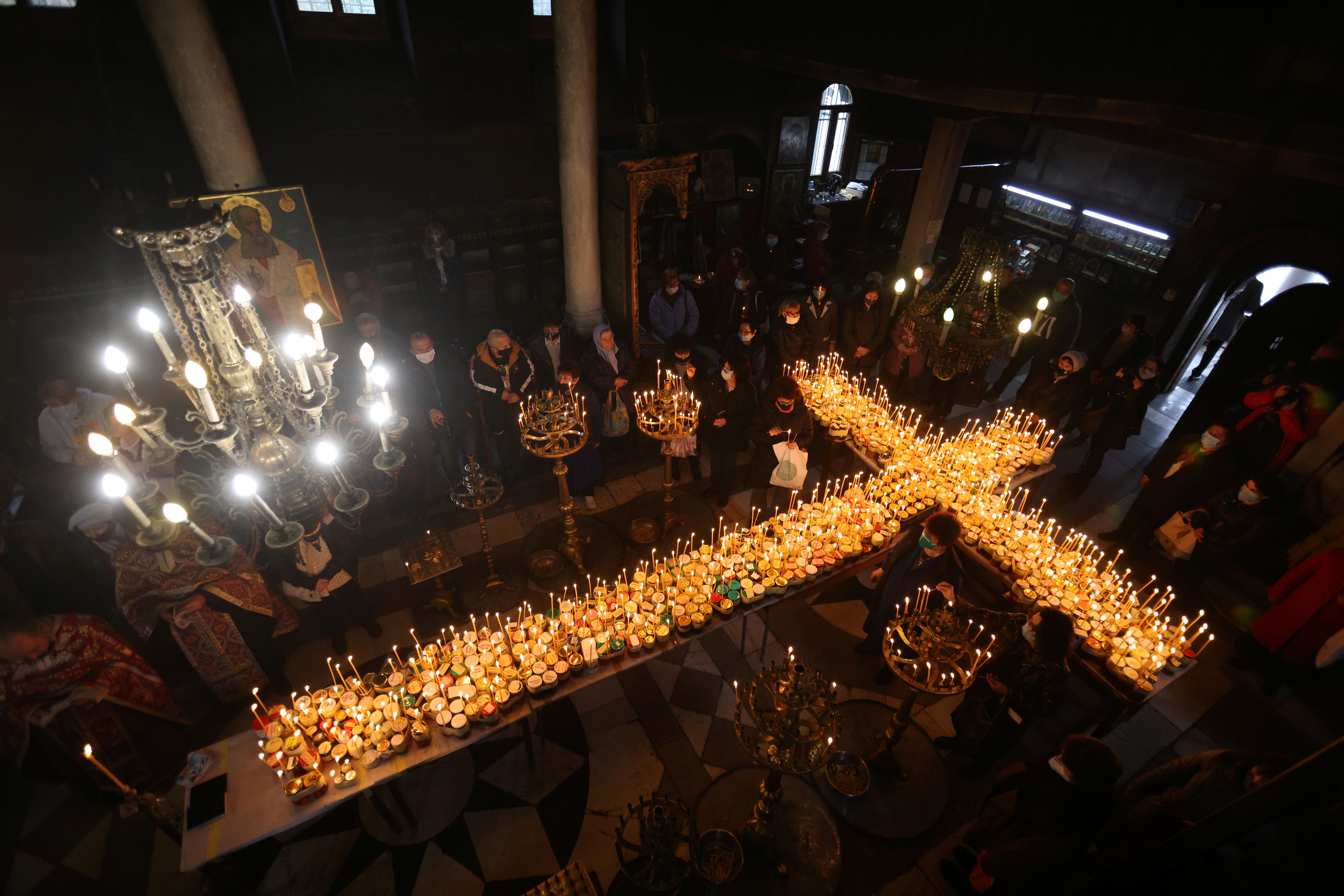 Worshippers gather around candles stuck to jars with honey during a religious mass in Blagoevgrad