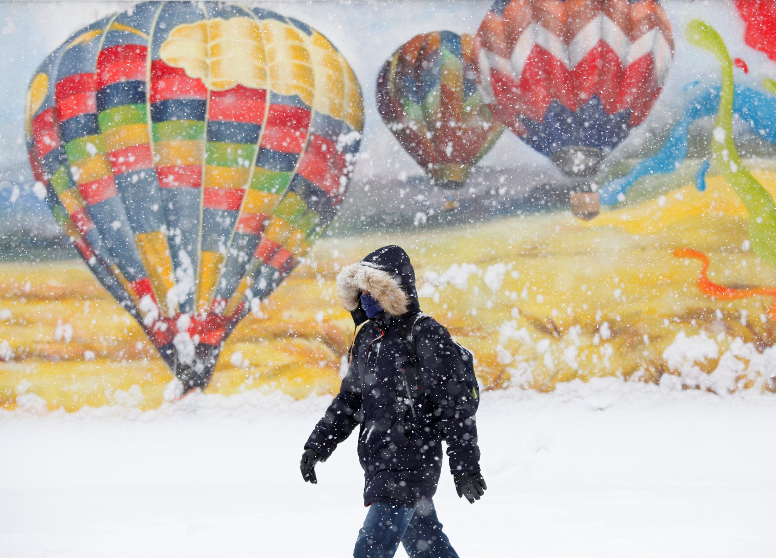 15022021 A man walks past a graffiti during snowfall in Stavropol, Russia February 15, 2021. REUTERS/Eduard Korniyenko