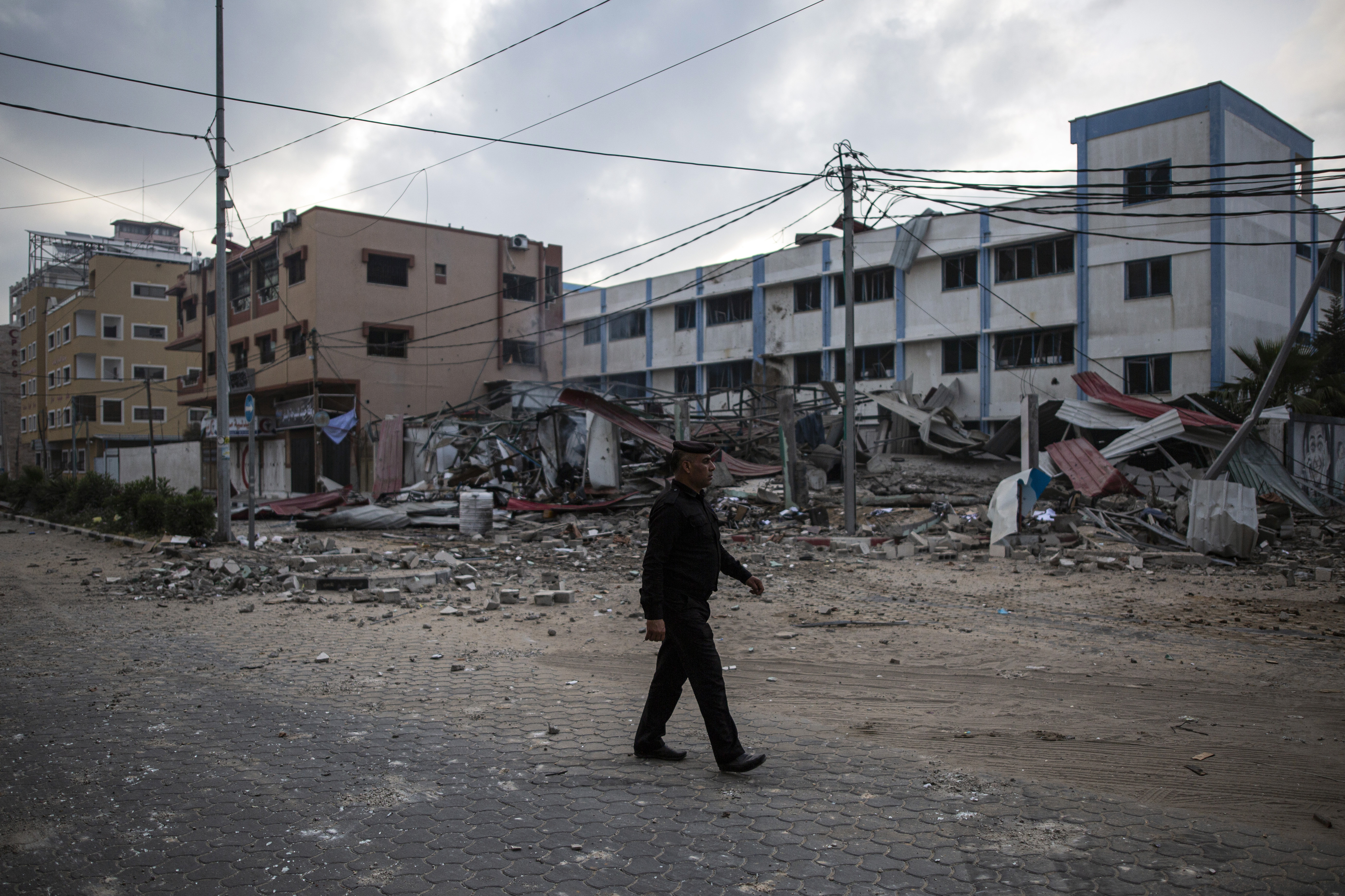 A Palestinian police officer crosses a street next to the remains of a Hamas security building which was hit by Israeli missile strikes, in Gaza City, early Tuesday, May. 11, 2021. (AP Photo/Khalil Hamra)