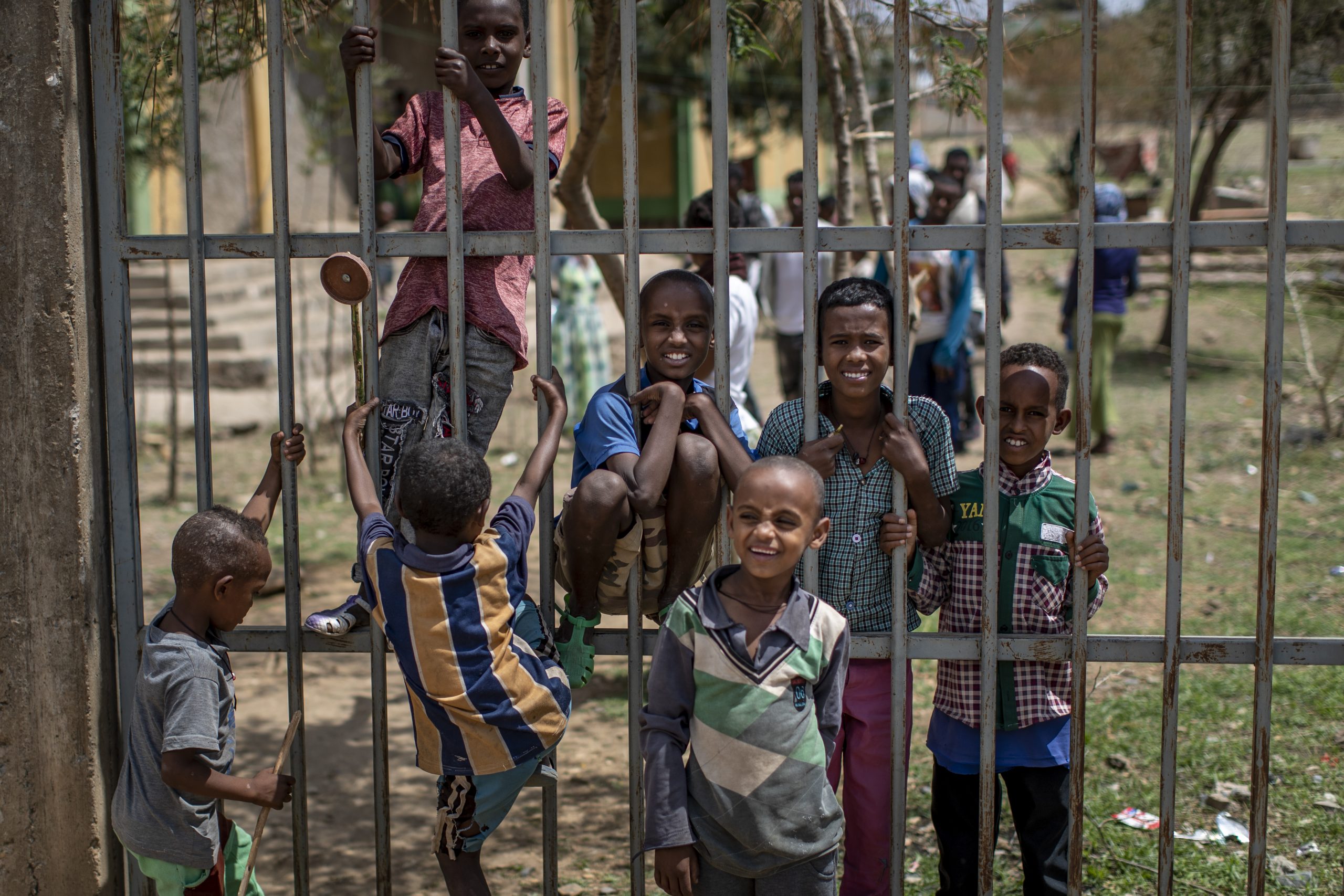 Children displaced by the conflict play on a metal fence at the elementary school where they now live with their families in the town of Abi Adi, in the Tigray region of northern Ethiopia Tuesday, May 11, 2021. (AP Photo/Ben Curtis)