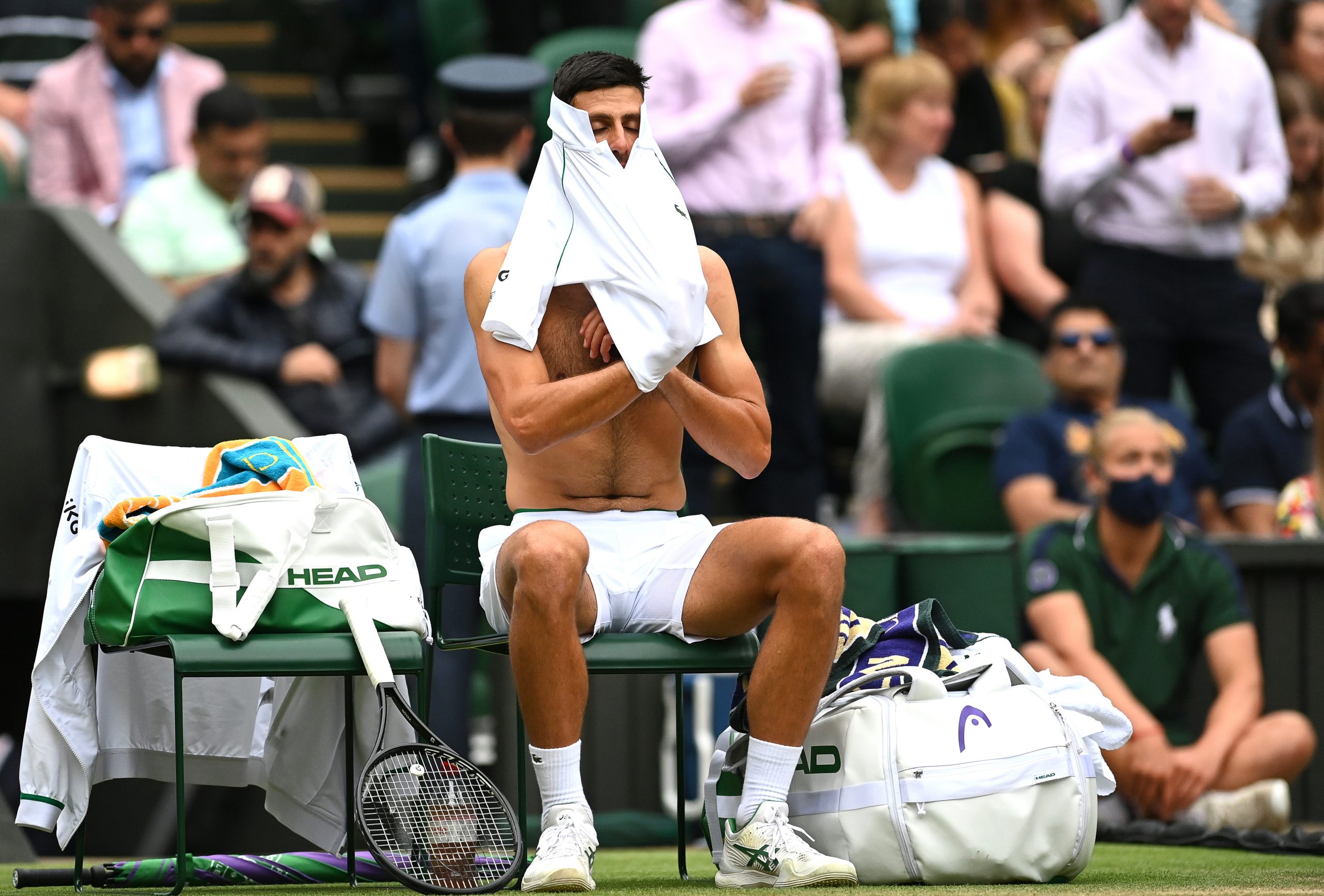 epa09334206 Novak Djokovic of Serbia changes his shirt during a break in his men's semi final match against Denis Shapovalov of Canada at the Wimbledon Championships in Wimbledon, Britain, 09 July 2021.  EPA-EFE/NEIL HALL   EDITORIAL USE ONLY