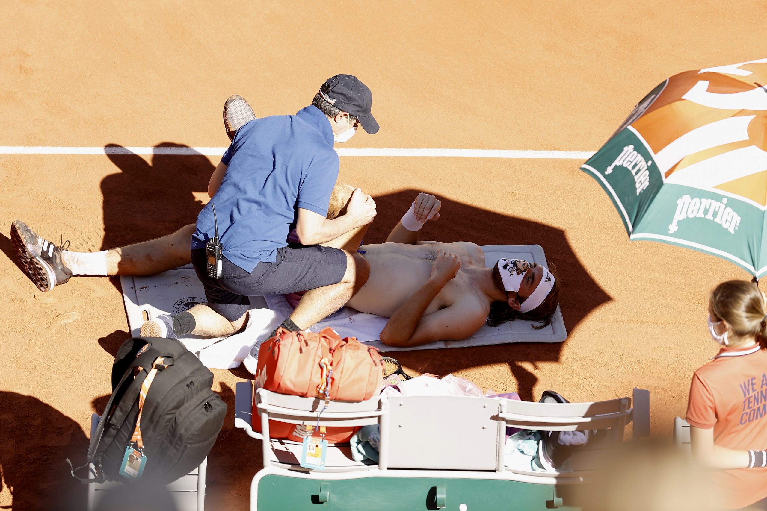 epa09267768 Stefanos Tsitsipas of Greece receives medical treatment during his final match against Novak Djokovic of Serbia at the French Open tennis tournament at Roland Garros in Paris, France, 13 June 2021.  EPA-EFE/IAN LANGSDON