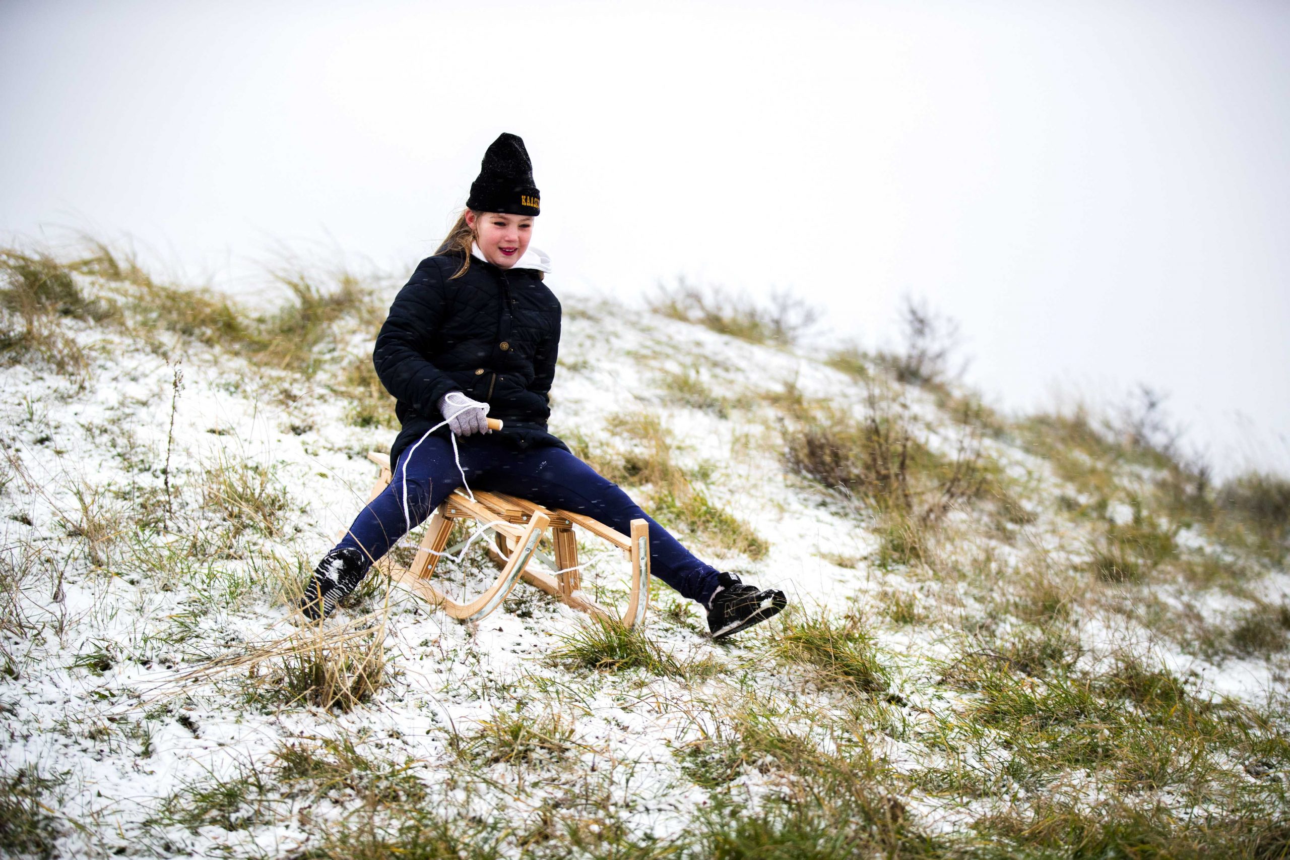 epa08942010 A girl sits on a sledge with little snow in Zandvoort, Netherlands, 16 January 2021. In some parts on the country snow fell around three centimeters high.  EPA-EFE/Remko de Waal