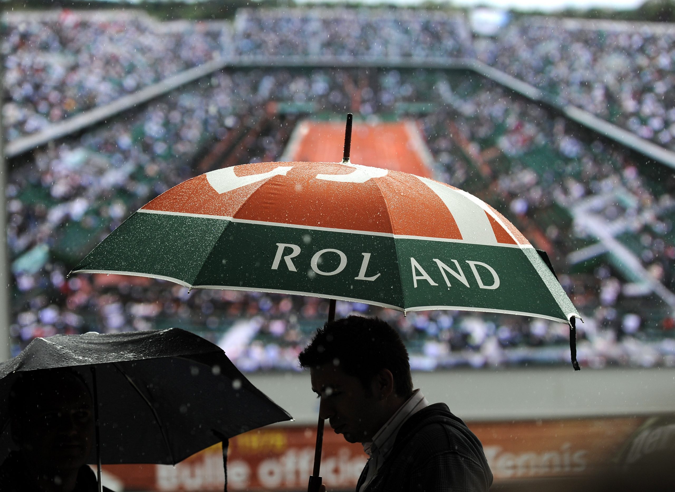 epa02175225 Tennis fans brave the elements as rain delays the start of play at the French Open tennis tournament at Roland Garros in Paris, France, 27 May 2010.  EPA/FELIPE TRUEBA