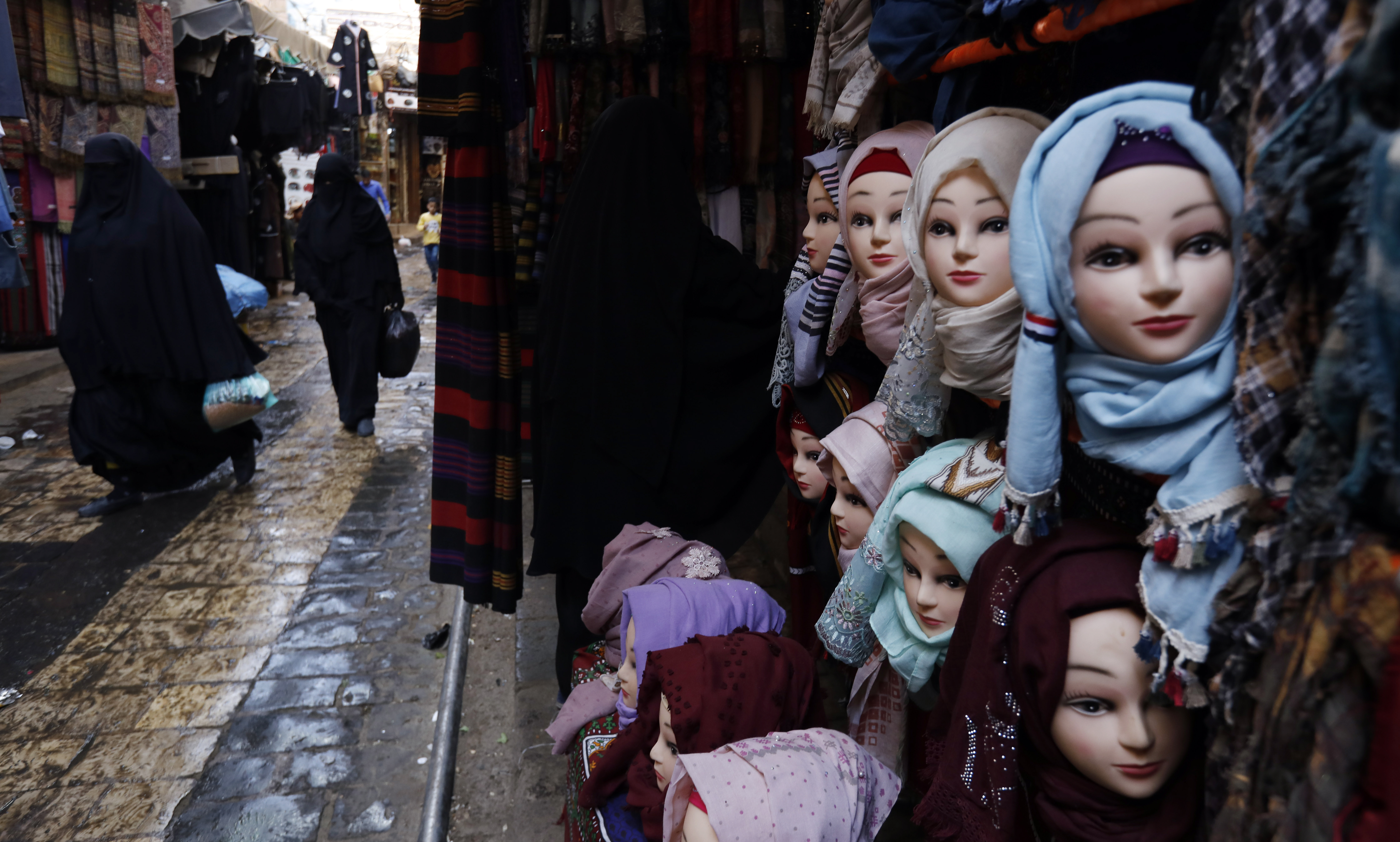 epa08220560 Women with burqa pass mannequins in Muslim headscarf hijab, at a market in Sanaa, Yemen 15 February 2020.  EPA-EFE/YAHYA ARHAB
