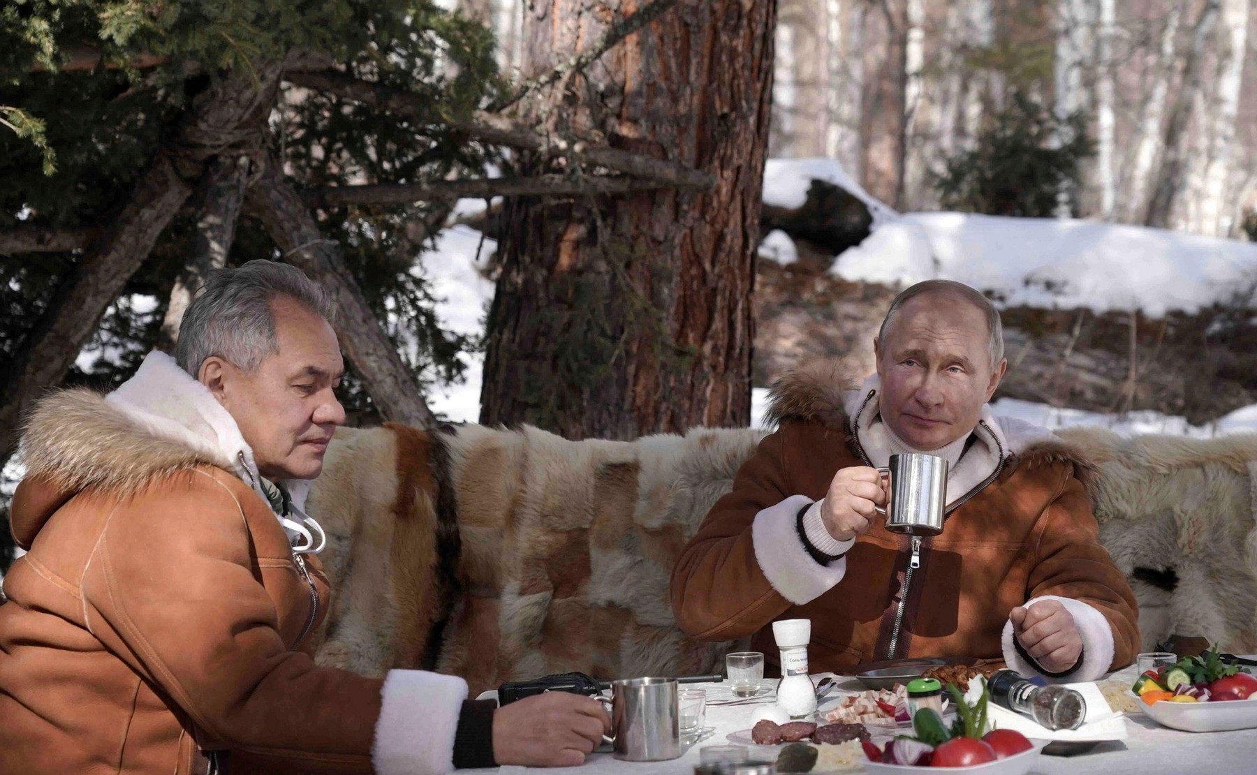 Tuva, Russia. 21st Mar, 2021. Russian President Vladimir Putin takes a lunch break with Defense Minister Sergei Shoigu, left, during a weekend trip to the Russian Siberian taiga forest March 21, 2021 in Tuva, Russia. Credit: Planetpix/Alamy Live News