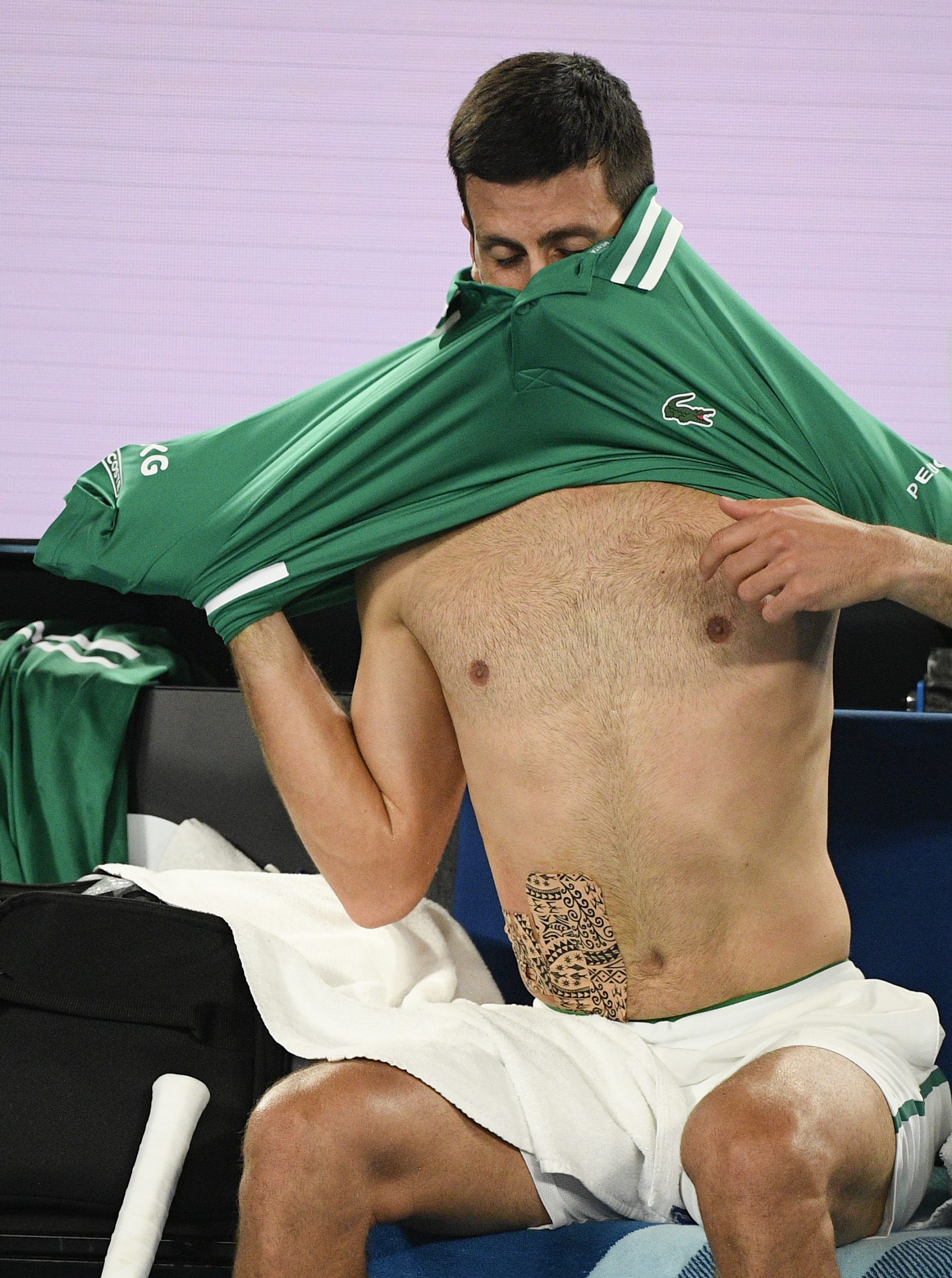 Serbia's Novak Djokovic changes his shirt after the third set against Germany's Alexander Zverev at the Australian Open tennis championship in Melbourne, Australia, Tuesday, Feb. 16, 2021.(AP Photo/Andy Brownbill)