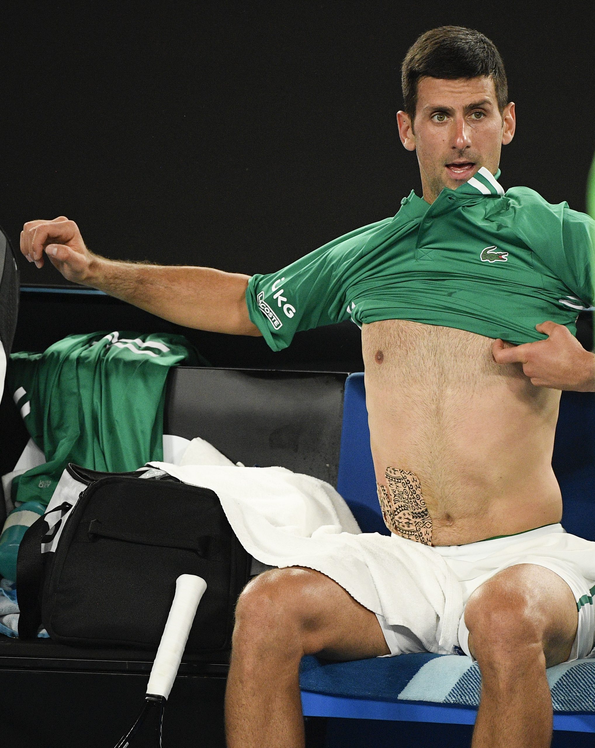 Serbia's Novak Djokovic changes his shirt after the third set against Germany's Alexander Zverev at the Australian Open tennis championship in Melbourne, Australia, Tuesday, Feb. 16, 2021.(AP Photo/Andy Brownbill)