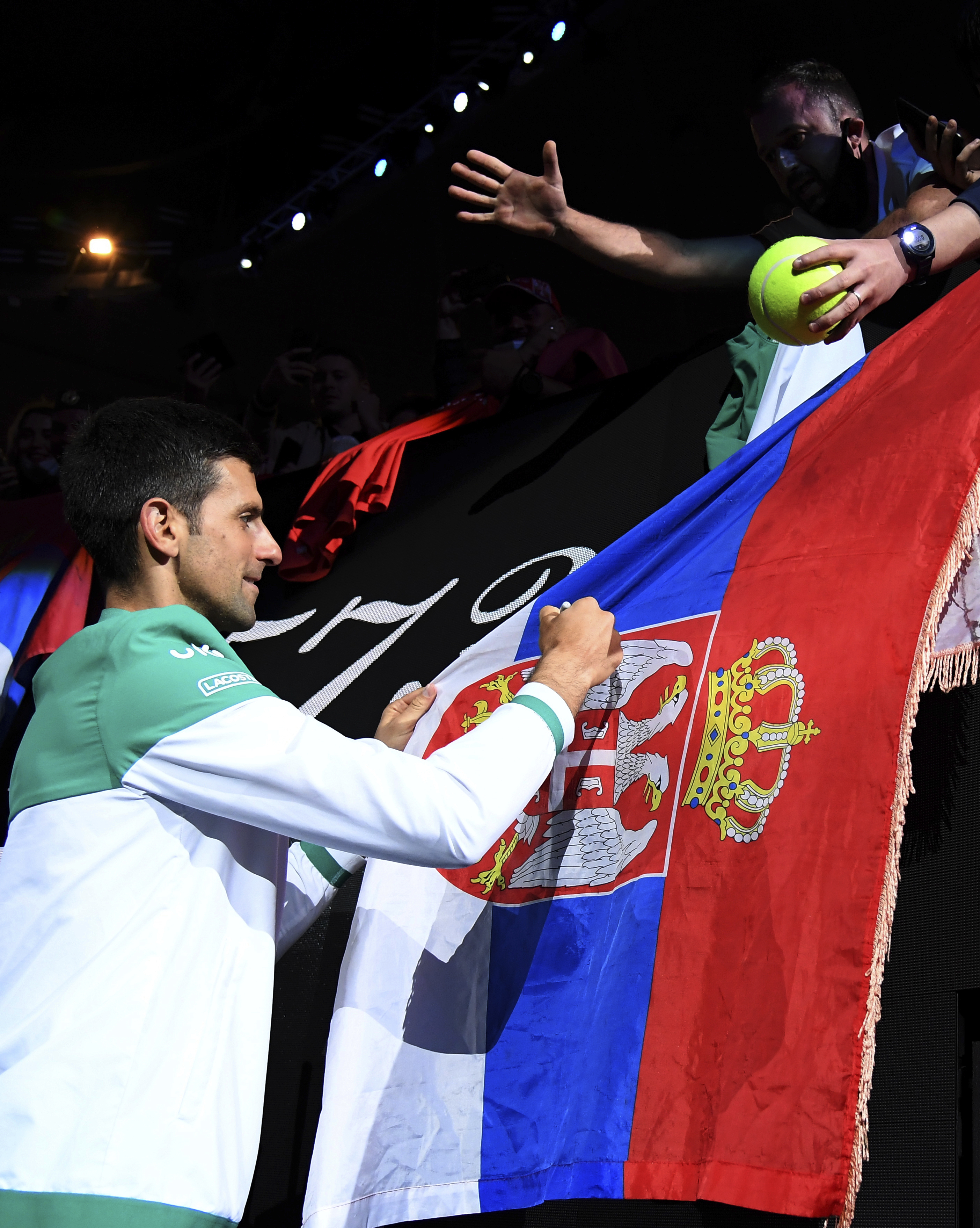 Serbia's Novak Djokovic signs autographs after defeating Russia's Daniil Medvedev during the men's singles final at the Australian Open tennis championship in Melbourne, Australia, Sunday, Feb. 21, 2021.(AP Photo/Andy Brownbill)