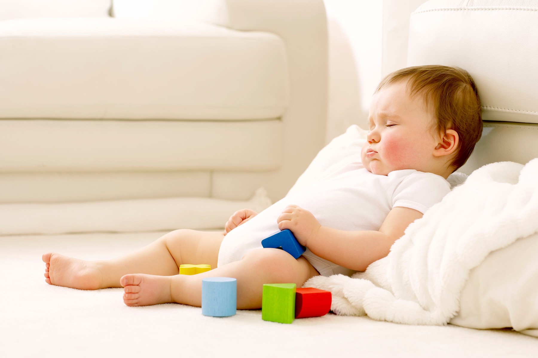 MODEL RELEASED. Sleeping baby. Baby boy sleeping against a sofa surrounded by toy blocks.,Image: 101529617, License: Royalty-free, Restrictions: , Model Release: yes, Credit line: RUTH JENKINSON / Sciencephoto / Profimedia