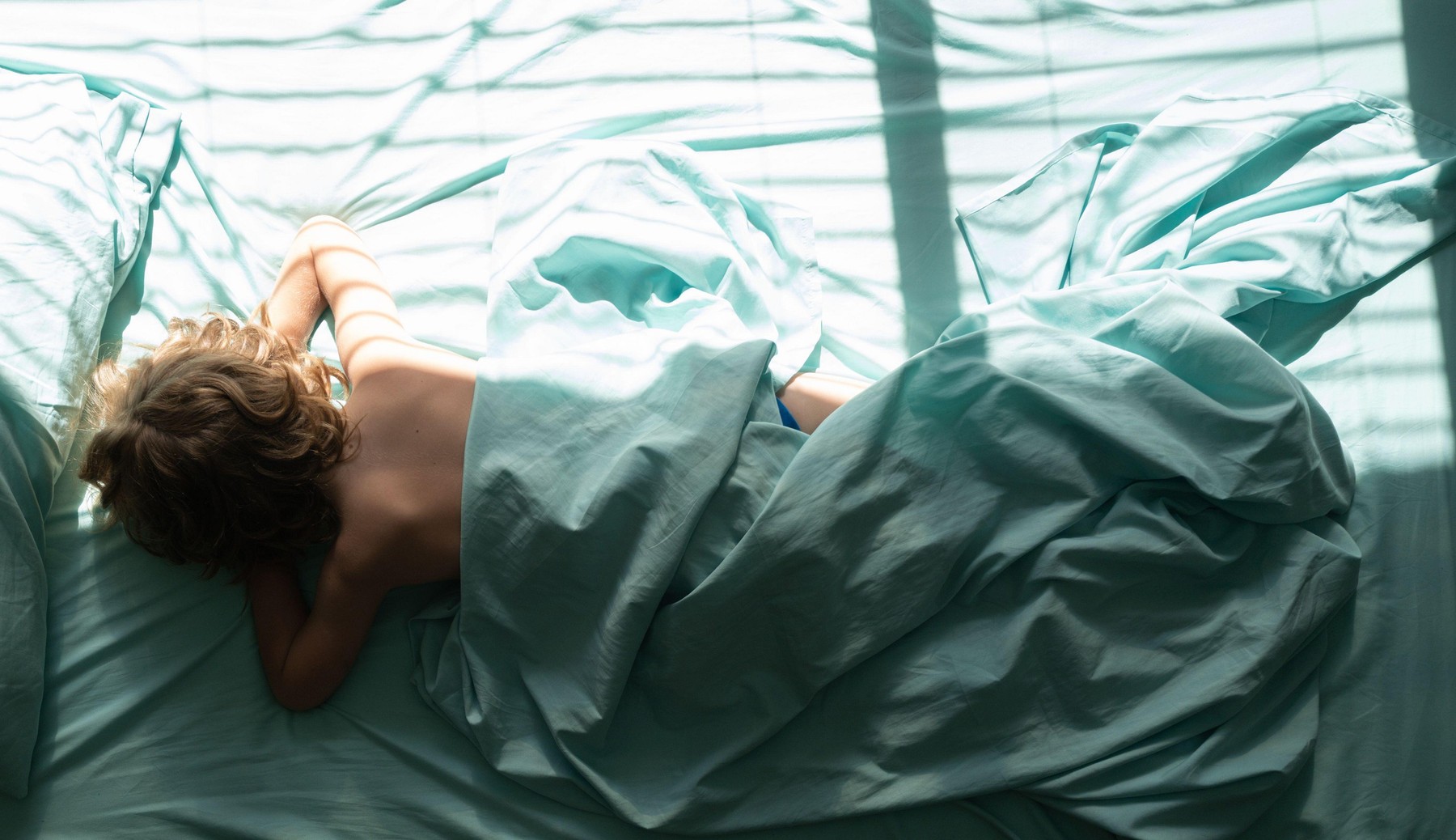 Child is laying down and sleeps on pillow. Top view of kids sleeping cozily on a bed in Bedroom at Morning.