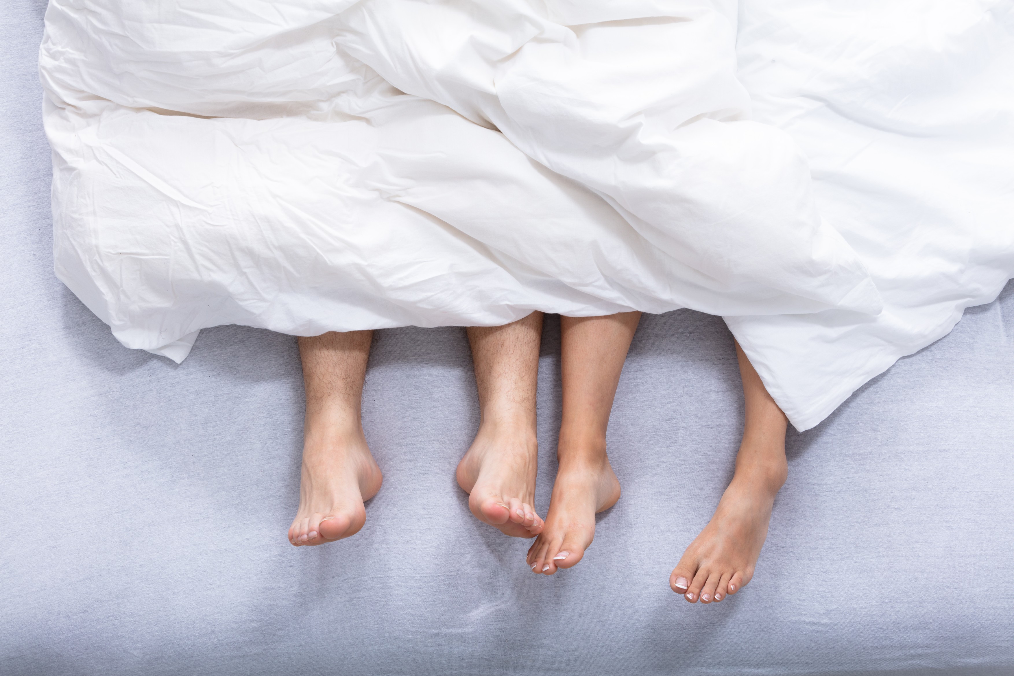 Feet Of Couple On Bed