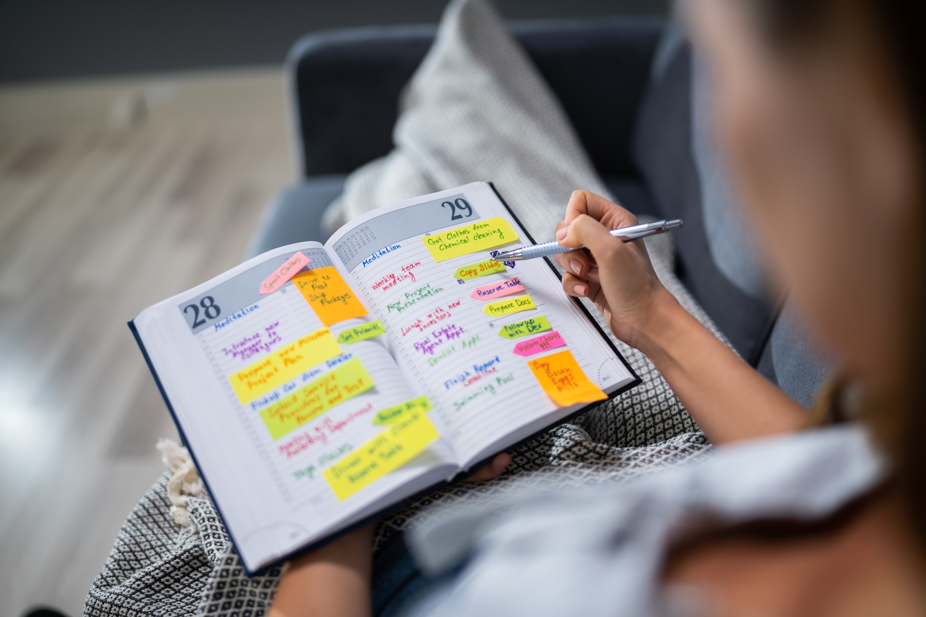Woman Making List Of Office Work In Diary