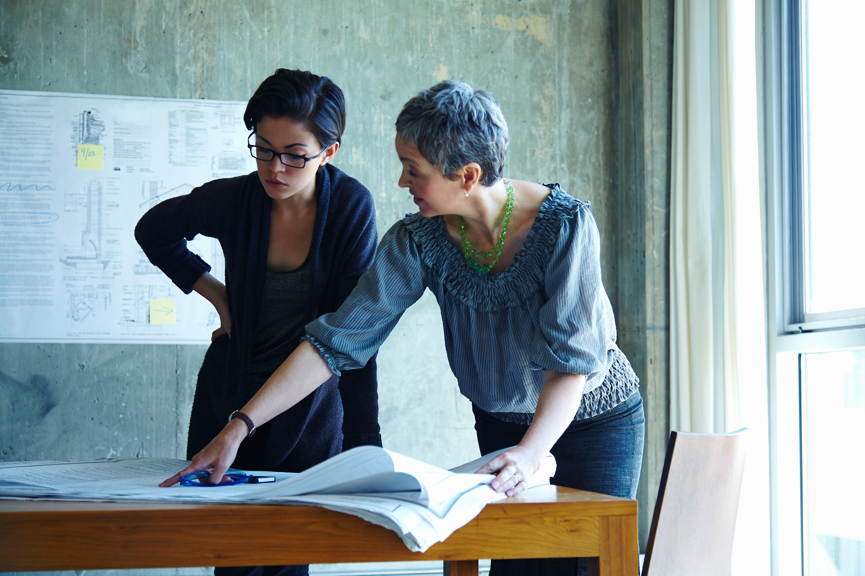 Two businesswomen studying blueprints in office