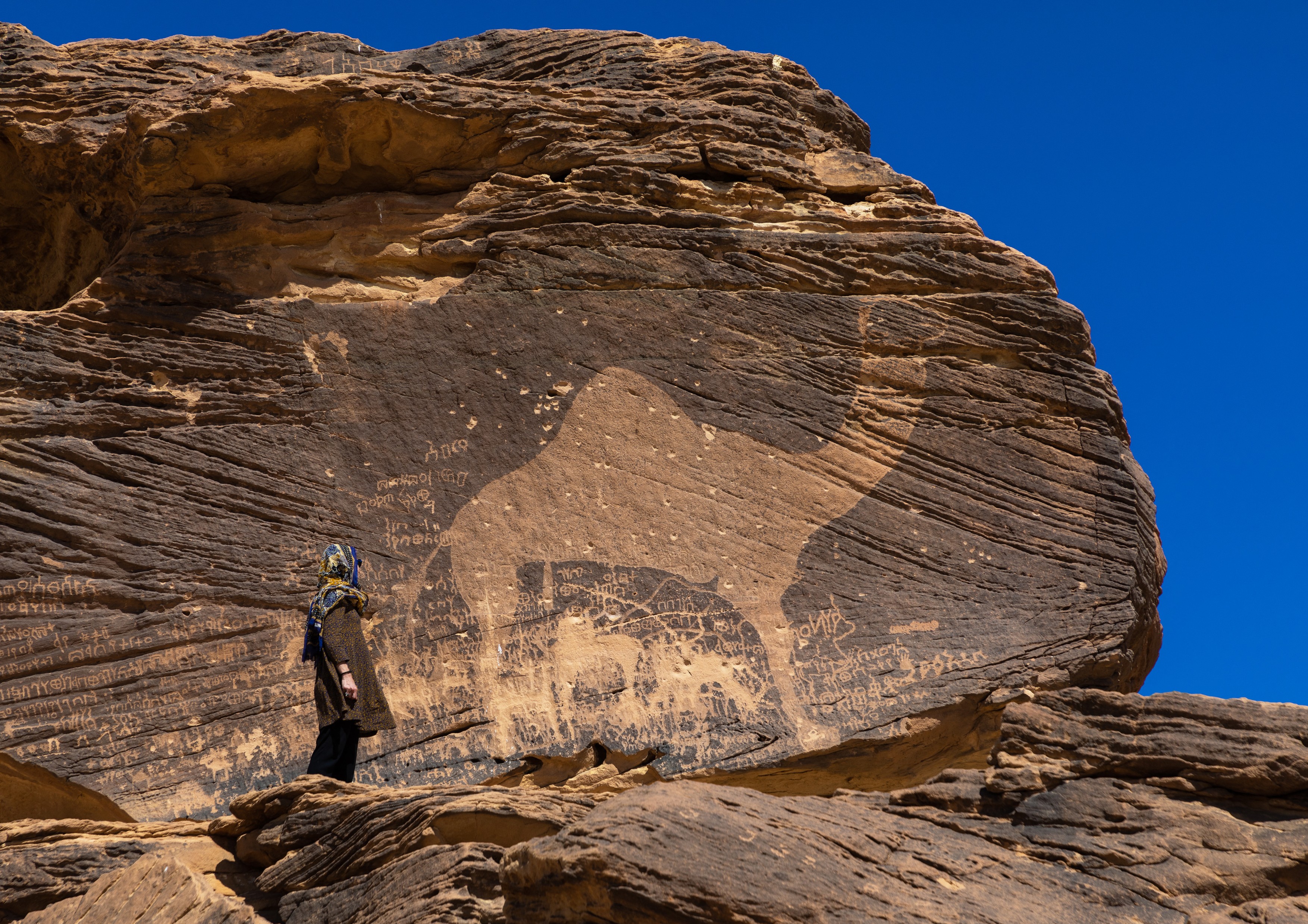 Tourist standing in front of a life-sized camel petroglyph on a rock, Najran Province, Thar, Saudi Arabia.,Image: 518457644, License: Rights-managed, Restrictions: , Model Release: no, Credit line: Eric Lafforgue / AFP / Profimedia