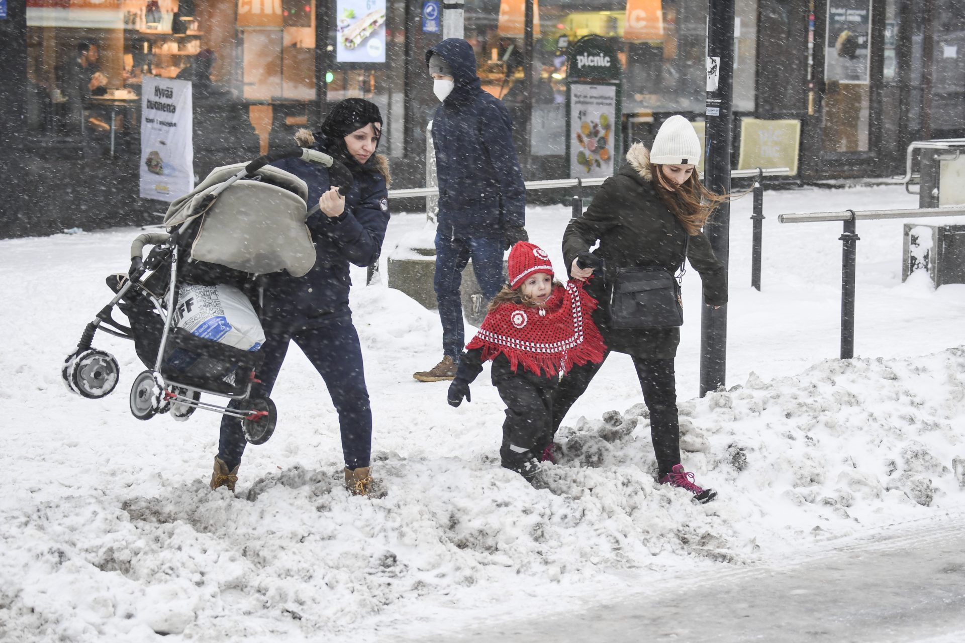 epa08932797 People cross a snow covered street in Helsinki, Finland, 12 January 2021, after a snowstorm swept across southern and south-western parts of the country.