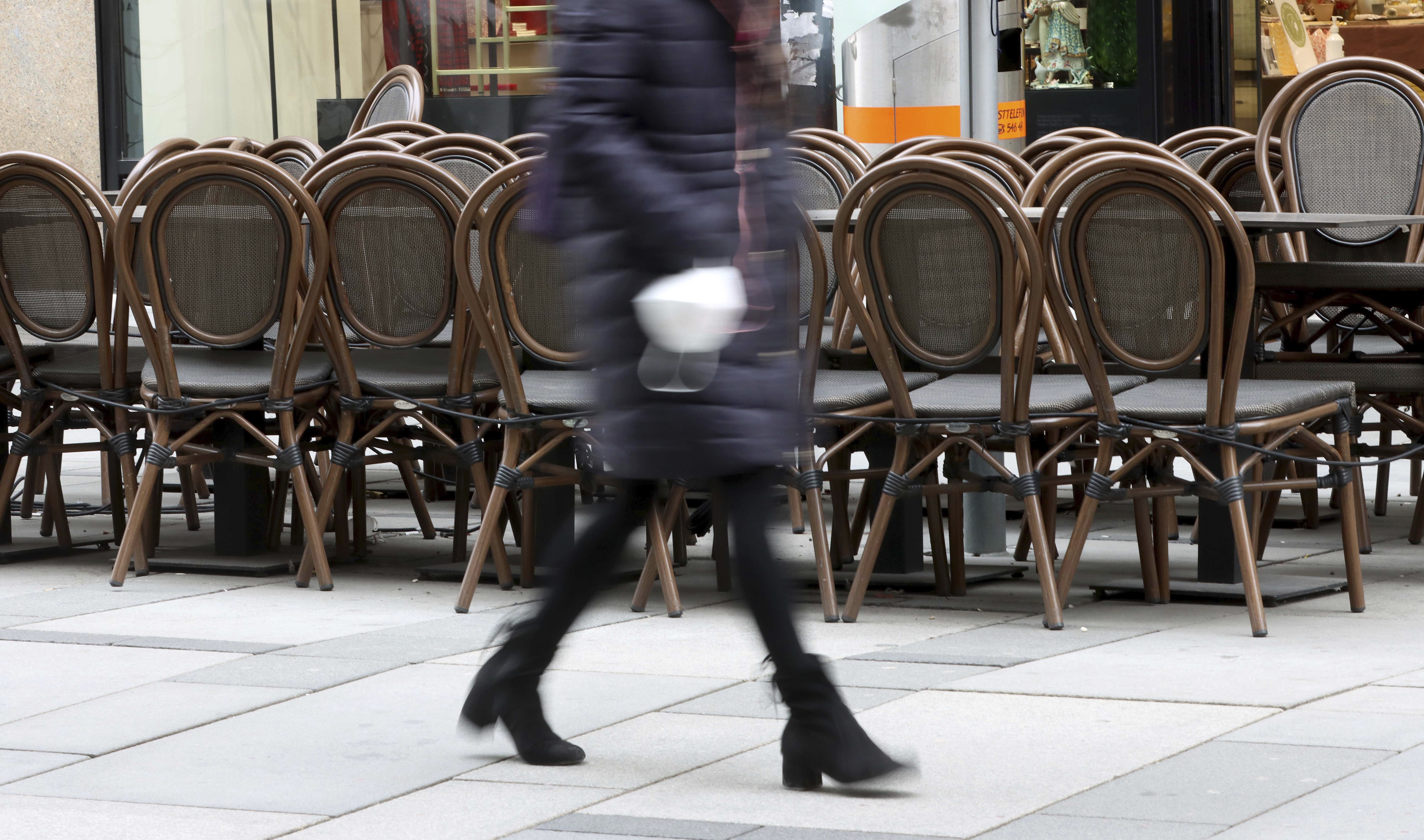 A person walks past a closed bar in downtown in Vienna, Austria, Monday, March 22, 2021. The Austrian government is considering on further measures to contain the coronavirus pandemic. (AP Photo/Ronald Zak)