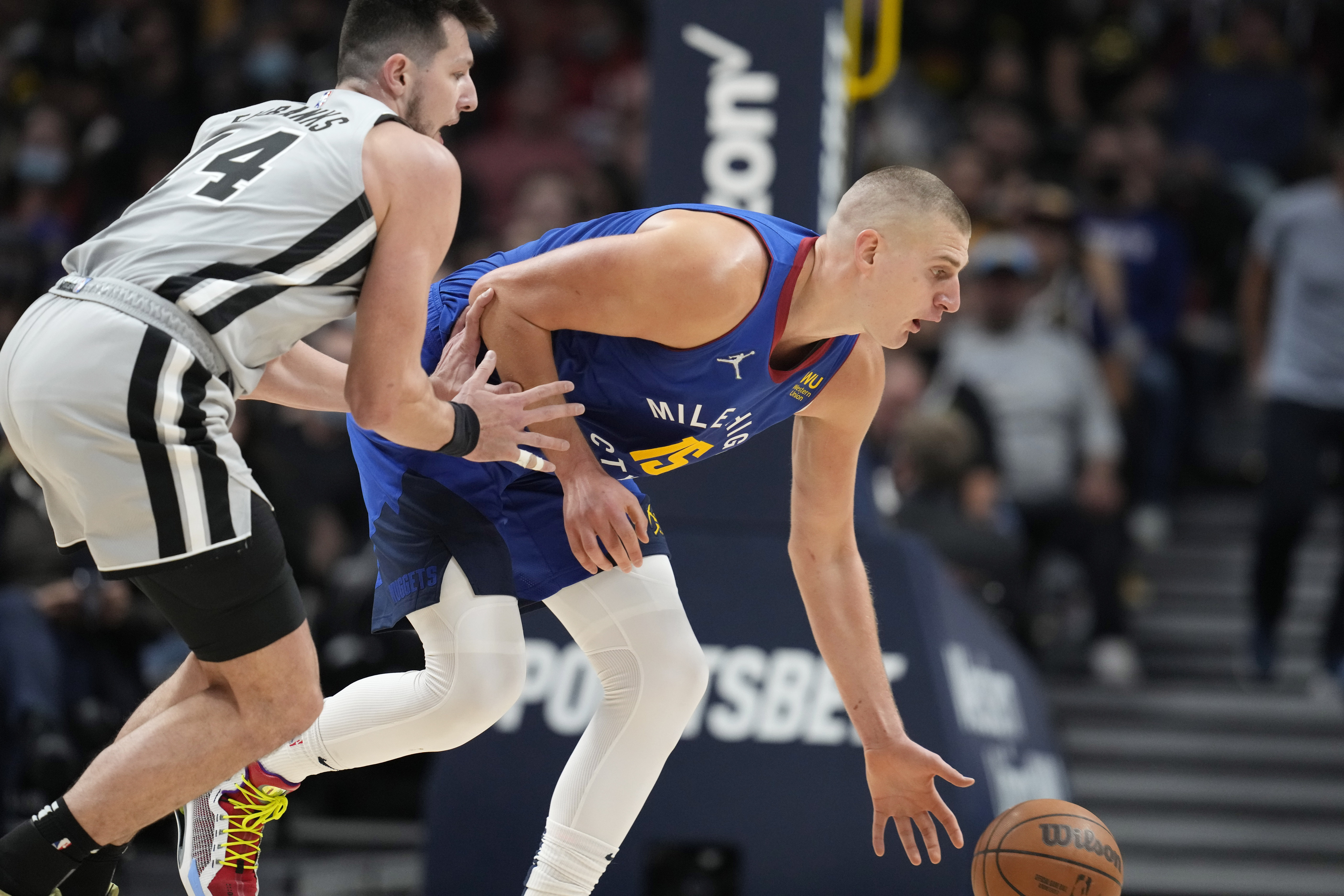 Denver Nuggets center Nikola Jokic, right, reaches out for the ball next to San Antonio Spurs forward Drew Eubanks during the second half of an NBA basketball game Friday, Oct. 22, 2021, in Denver. The Nuggets won 102-96. (AP Photo/David Zalubowski)