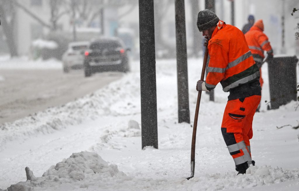 Municipal workers trying to clear a sidewalk from the snow in Gelsenkirchen, Germany, Monday, Feb. 8, 2021. Heavy snow falls hit hard the industrial Ruhr area. Parts of Germany are hit by strong winter weather. (AP Photo/Martin Meissner)