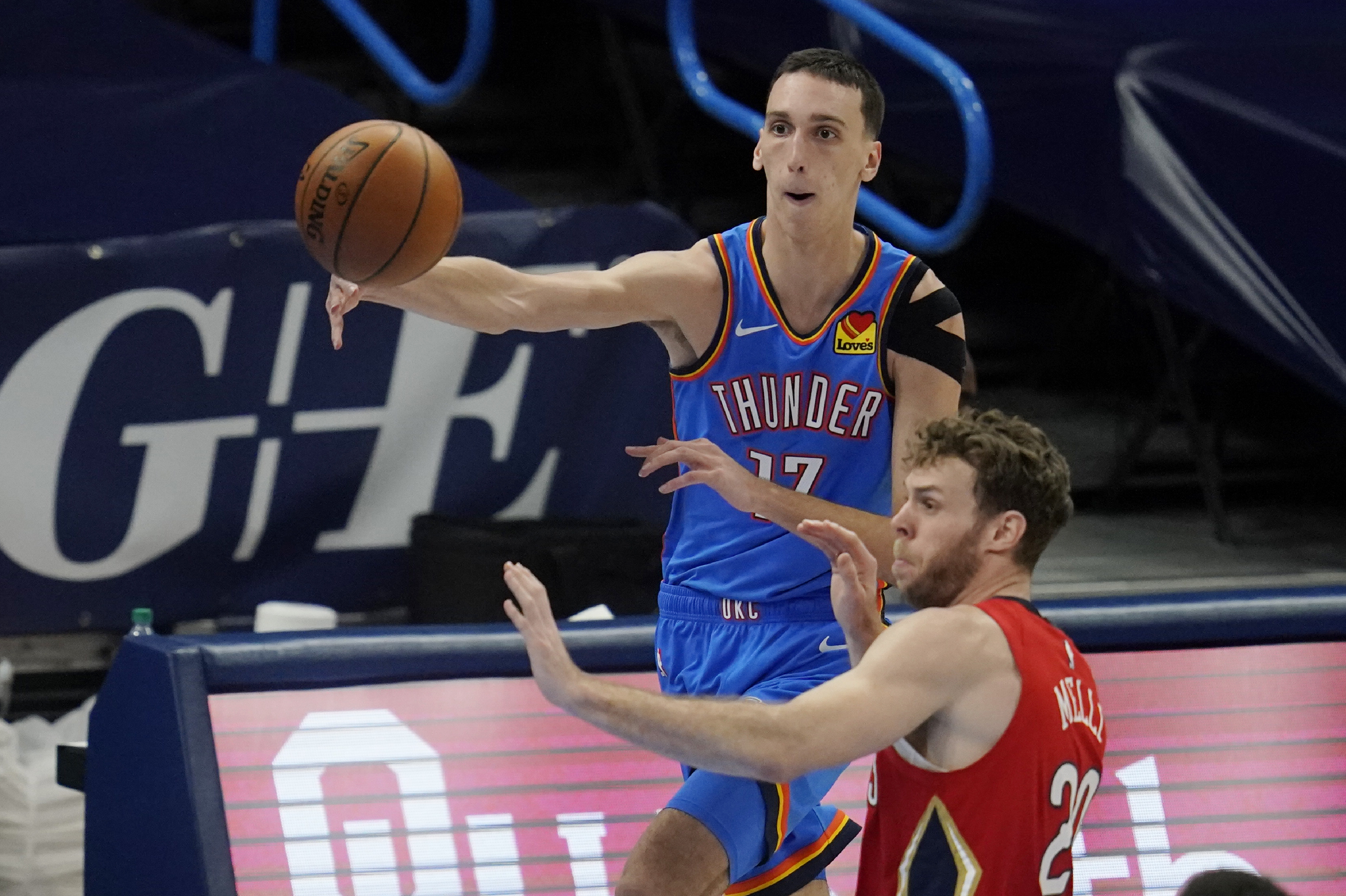 Oklahoma City Thunder forward Aleksej Pokusevski (17) passes in front of New Orleans Pelicans forward Nicolo Melli (20) in the second half of an NBA basketball game Thursday, Dec. 31, 2020, in Oklahoma City. (AP Photo/Sue Ogrocki)