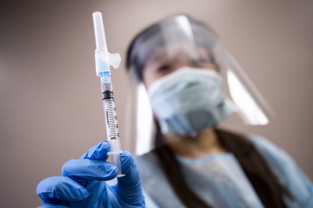 epa08746323 A nurse holds a syringe containing flu vaccine at a free mobile clinic in Lakewood, California, USA, 14 October 2020. Flu vaccine manufacturers have increased production in anticipation of this year's flu season.  EPA-EFE/ETIENNE LAURENT
