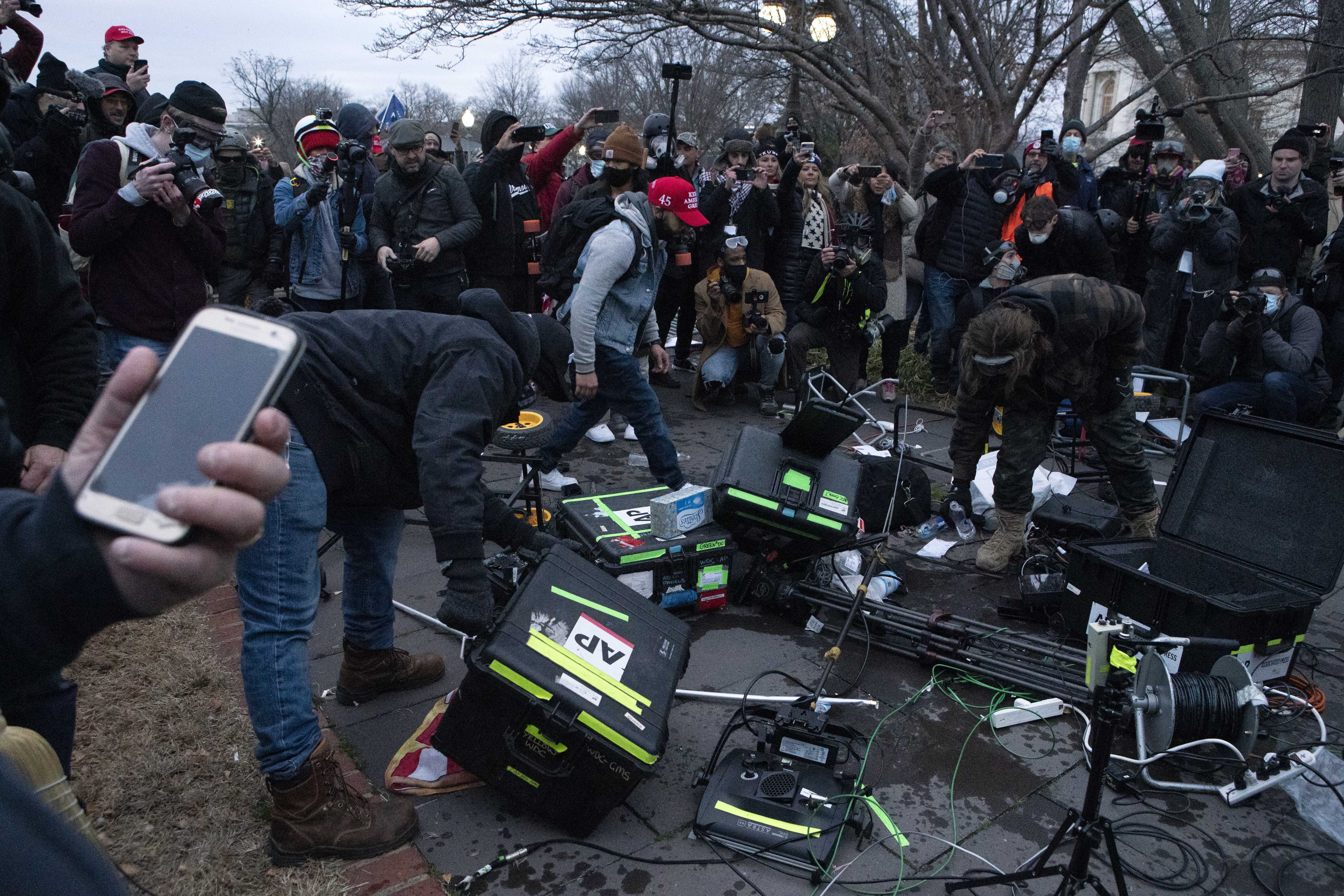 Demonstrators break TV equipment outside the the U.S. Capitol on Wednesday, Jan. 6, 2021, in Washington, during a chaotic protest aimed at thwarting a peaceful transfer of power. (AP Photo/Jose Luis Magana)